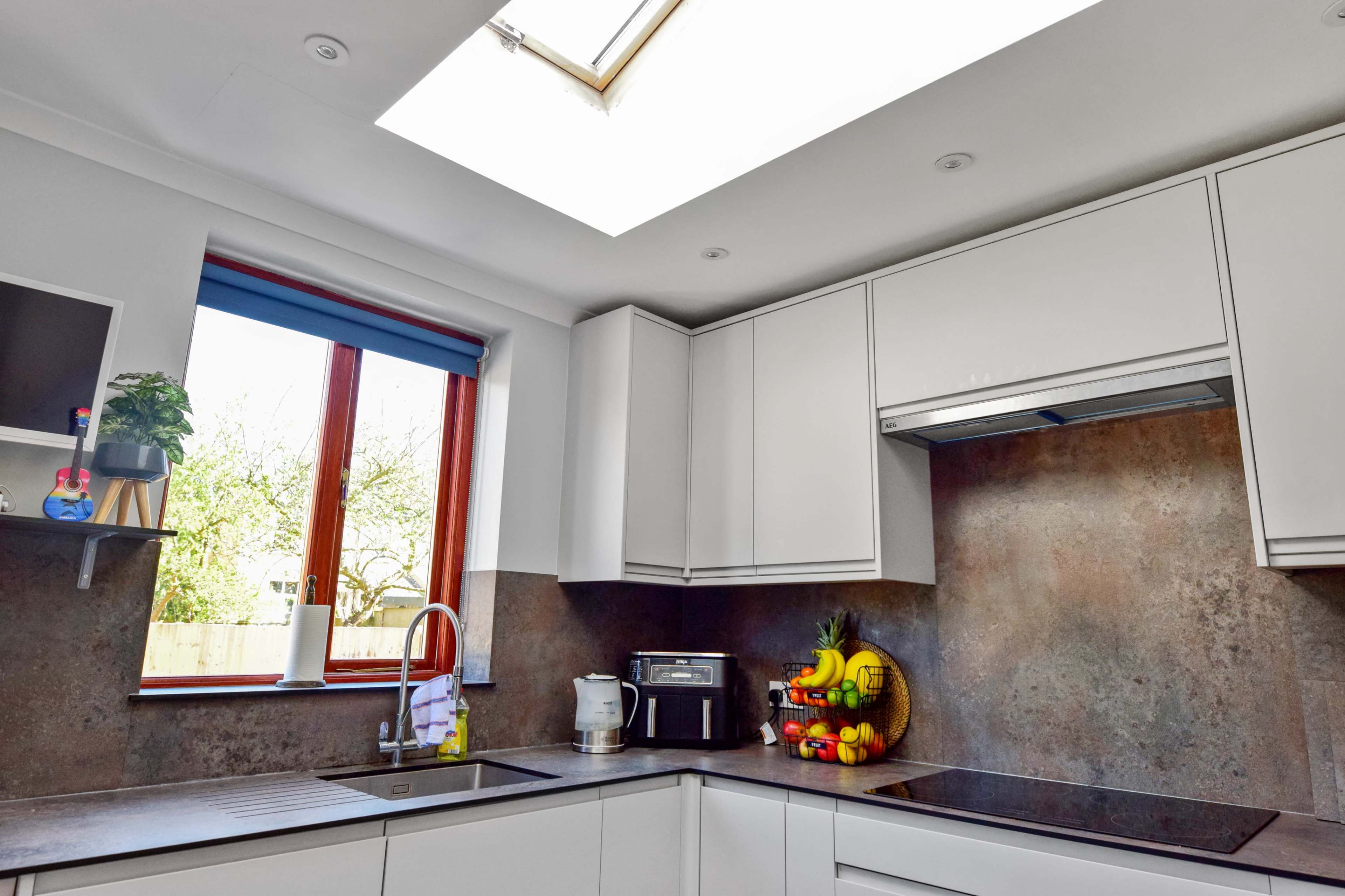A bright kitchen features a skylight, modern cabinetry, and a countertop with a fruit arrangement.
