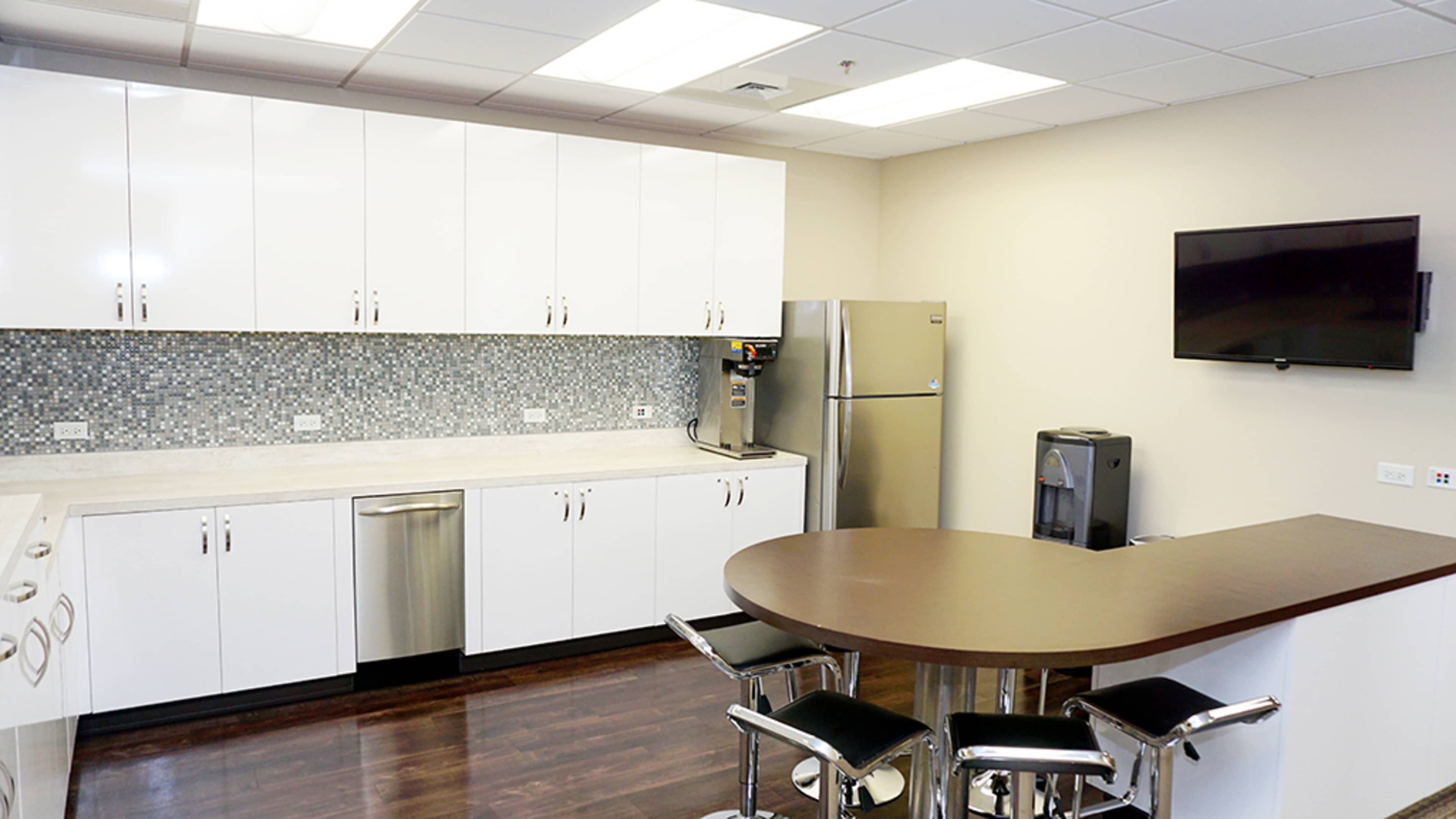 A modern kitchen with white cabinets, stainless steel appliances, and a dark wood countertop.