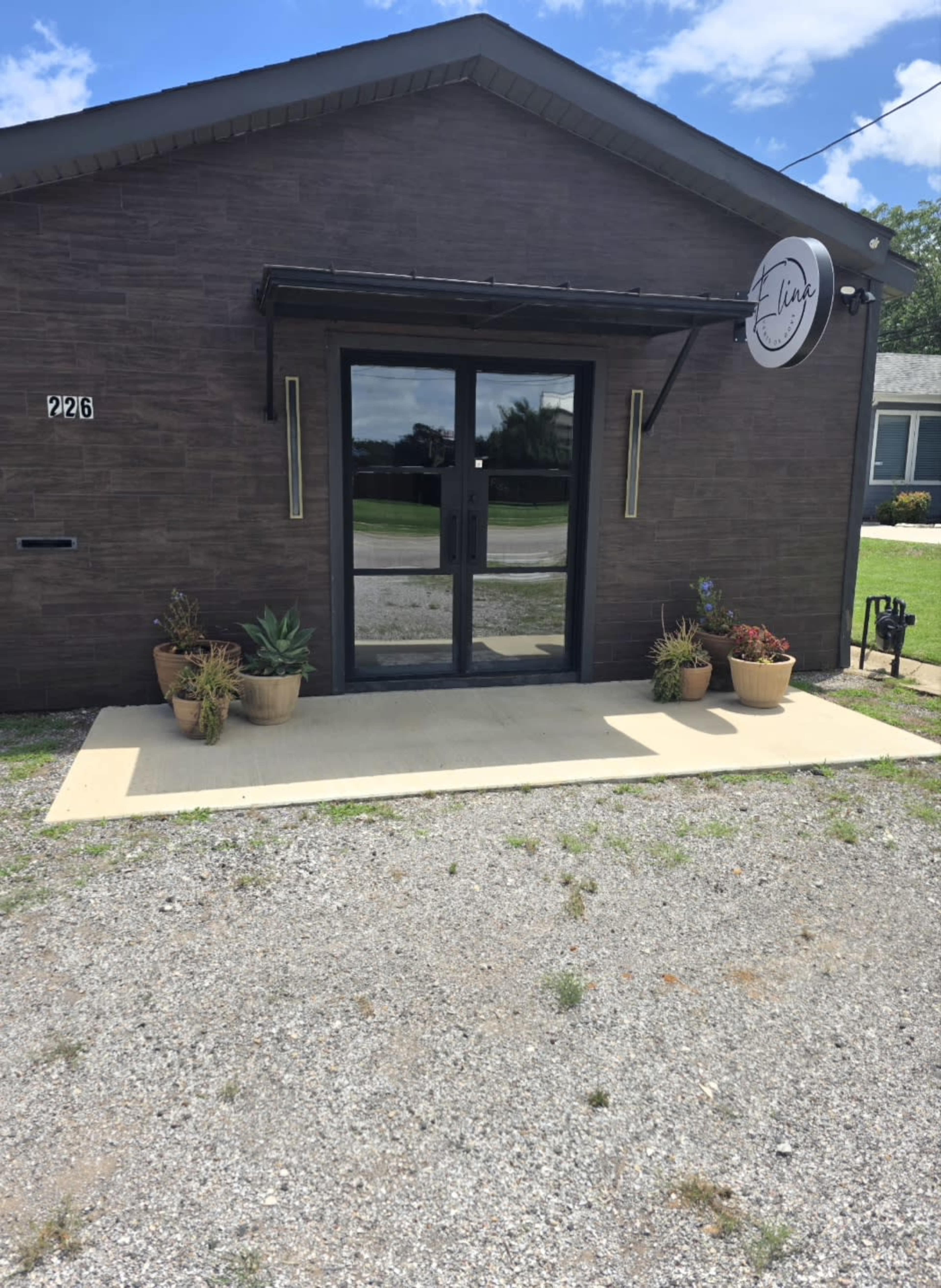 The image shows a dark brick building with a sign labeled "the line" above a glass entrance, surrounded by potted plants.