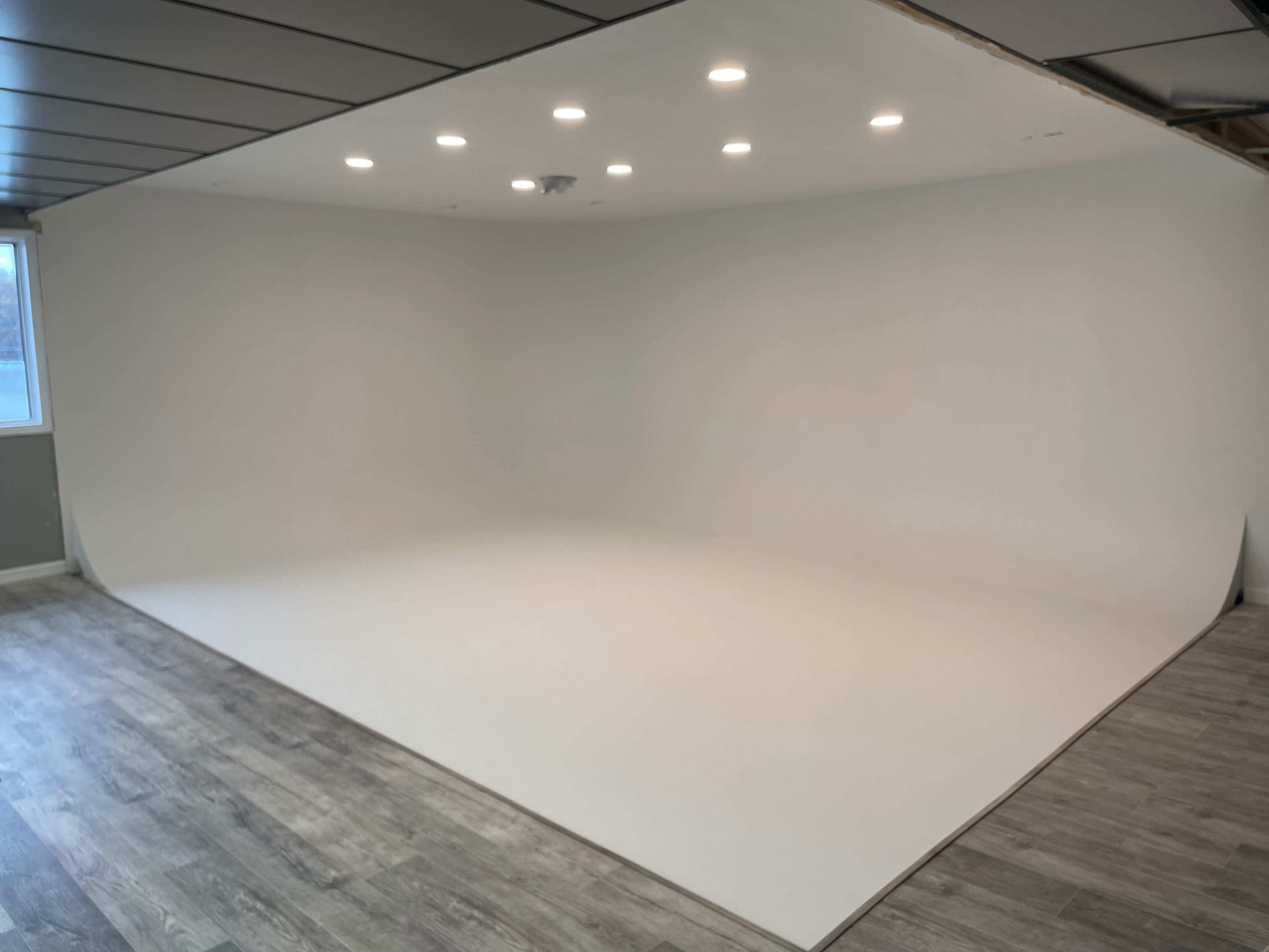A spacious studio with a curved white backdrop and multiple recessed lights overhead.