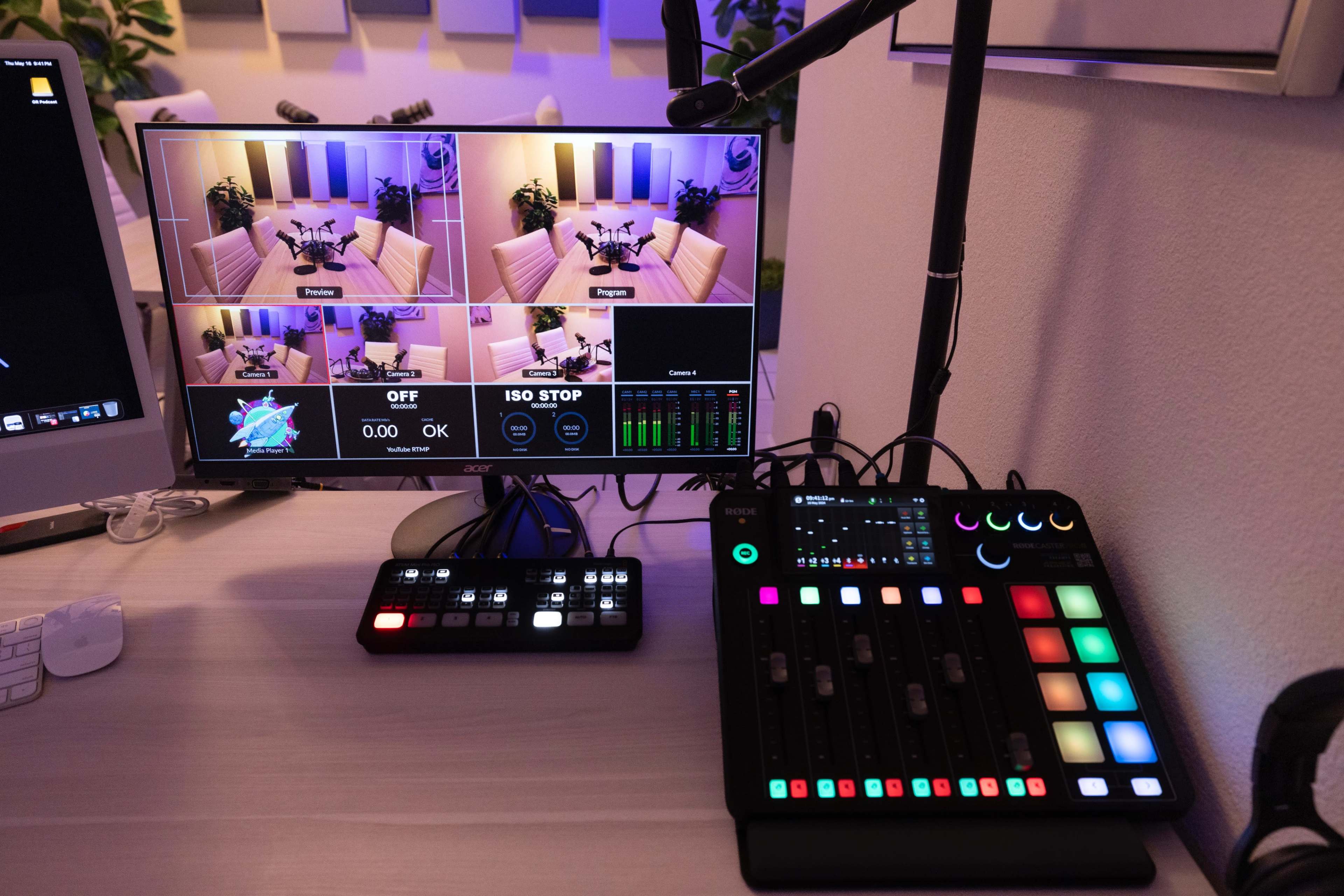 A computer monitor displaying multiple camera feeds and a control panel with colorful buttons and sliders on a desk.