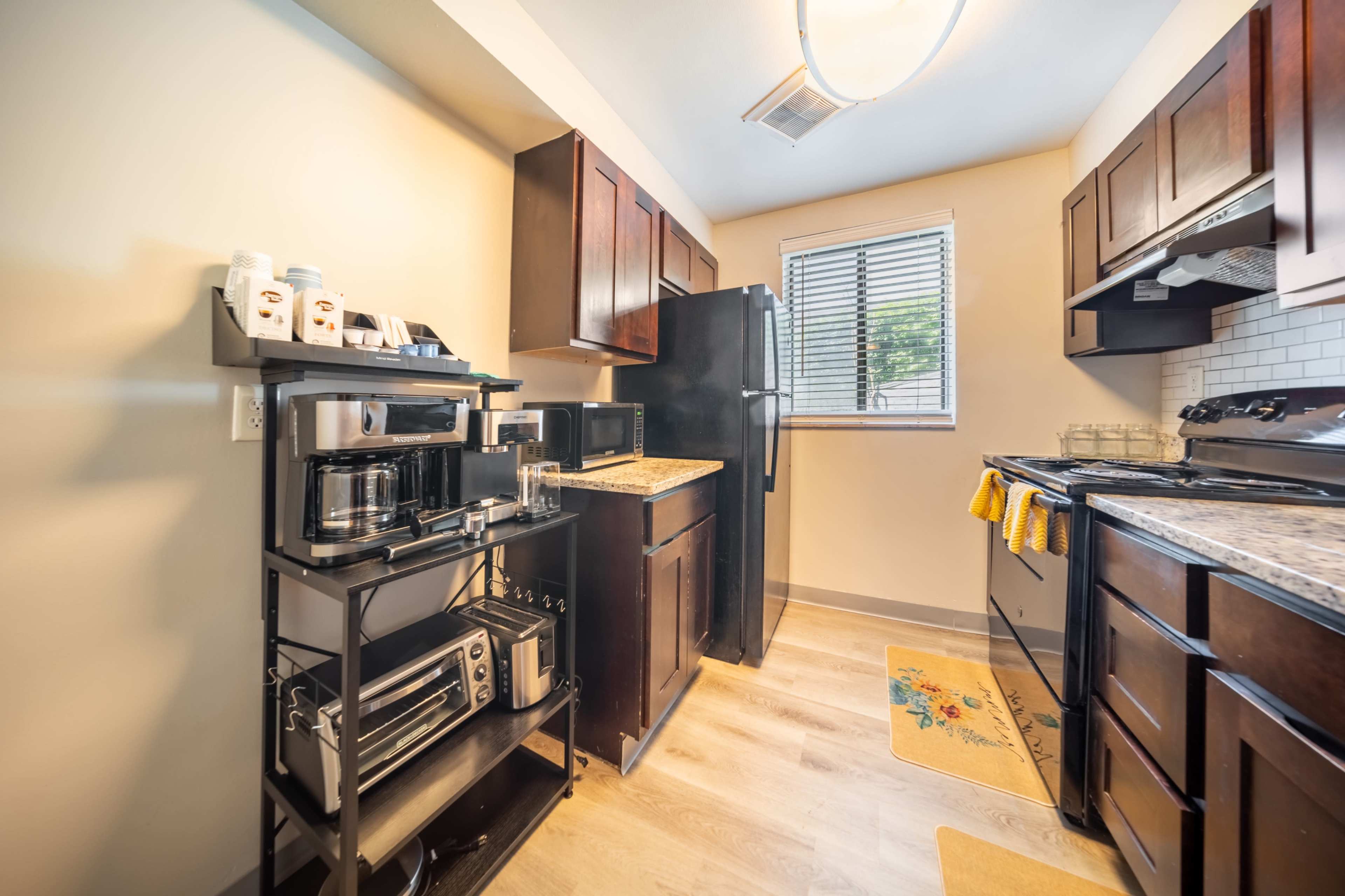 A compact kitchen featuring dark wooden cabinets, a black refrigerator, and an oven with a nearby countertop space.