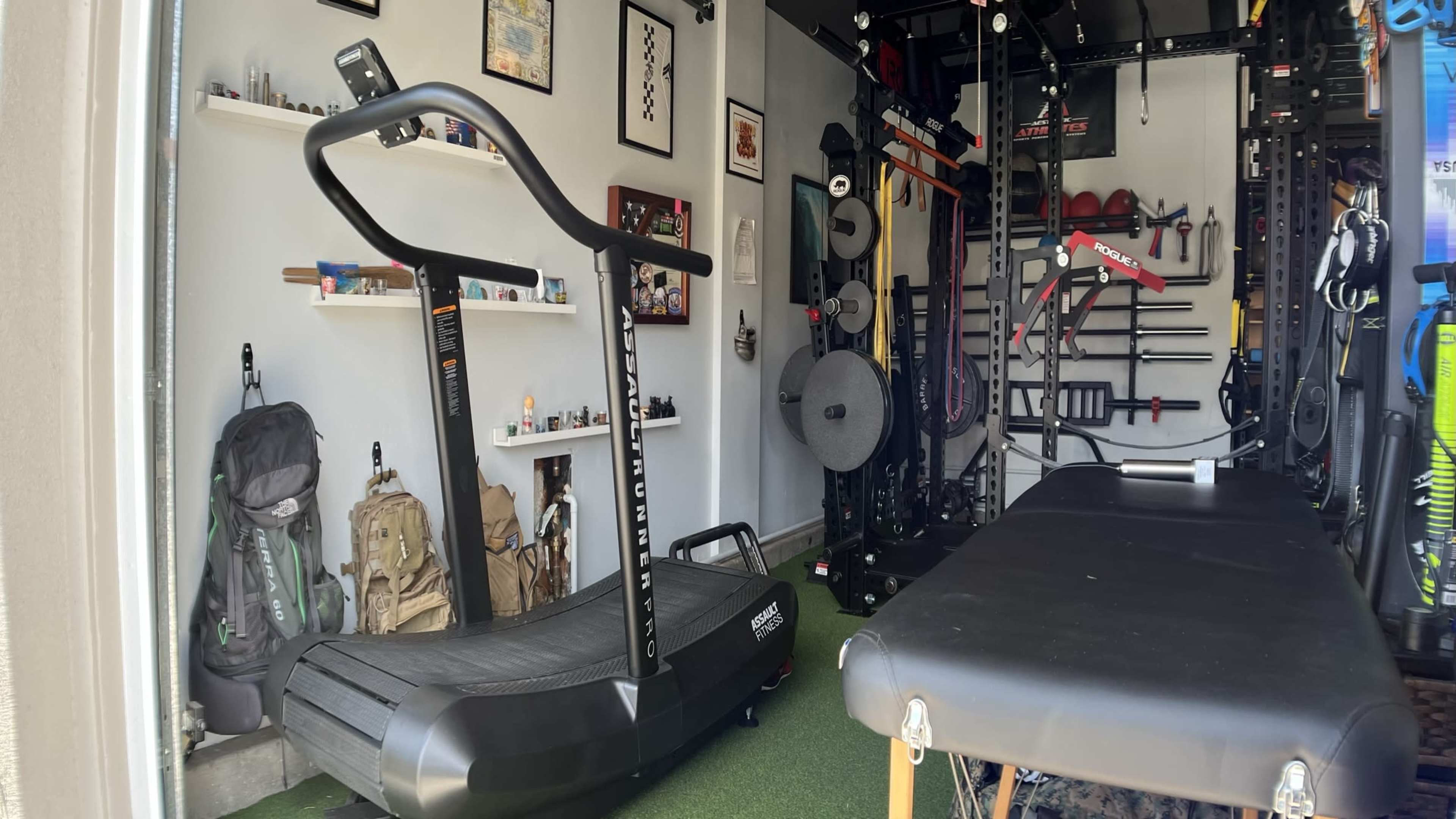 The image shows a home gym with a curved treadmill, exercise equipment mounted on walls, and a bench in a spacious room.