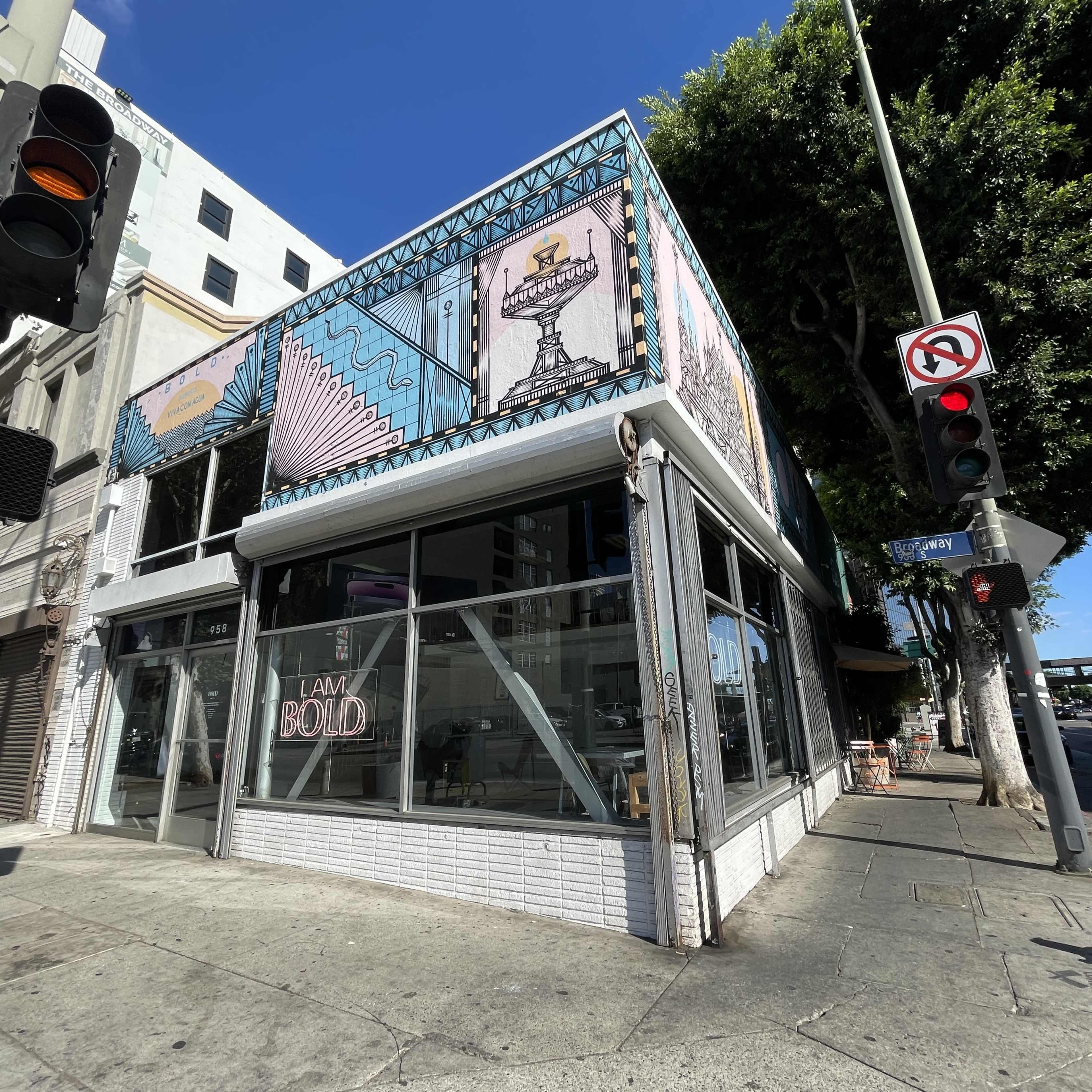 A corner building features a colorful mural and large windows with a "I AM BOLD" sign.