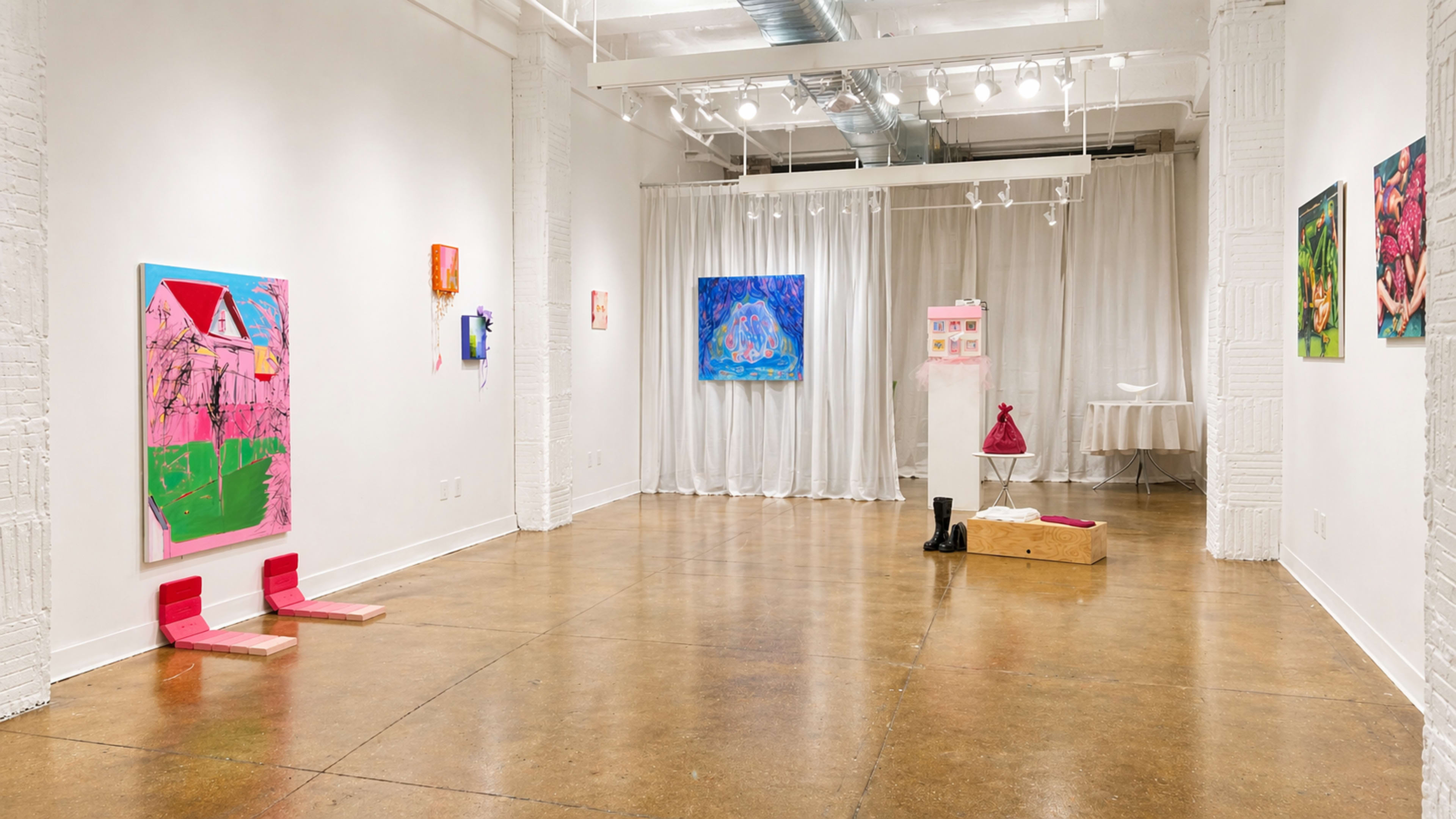 The image shows a contemporary art gallery featuring colorful paintings on the walls, a curtain separating a section of the space, and a wooden box on the floor.