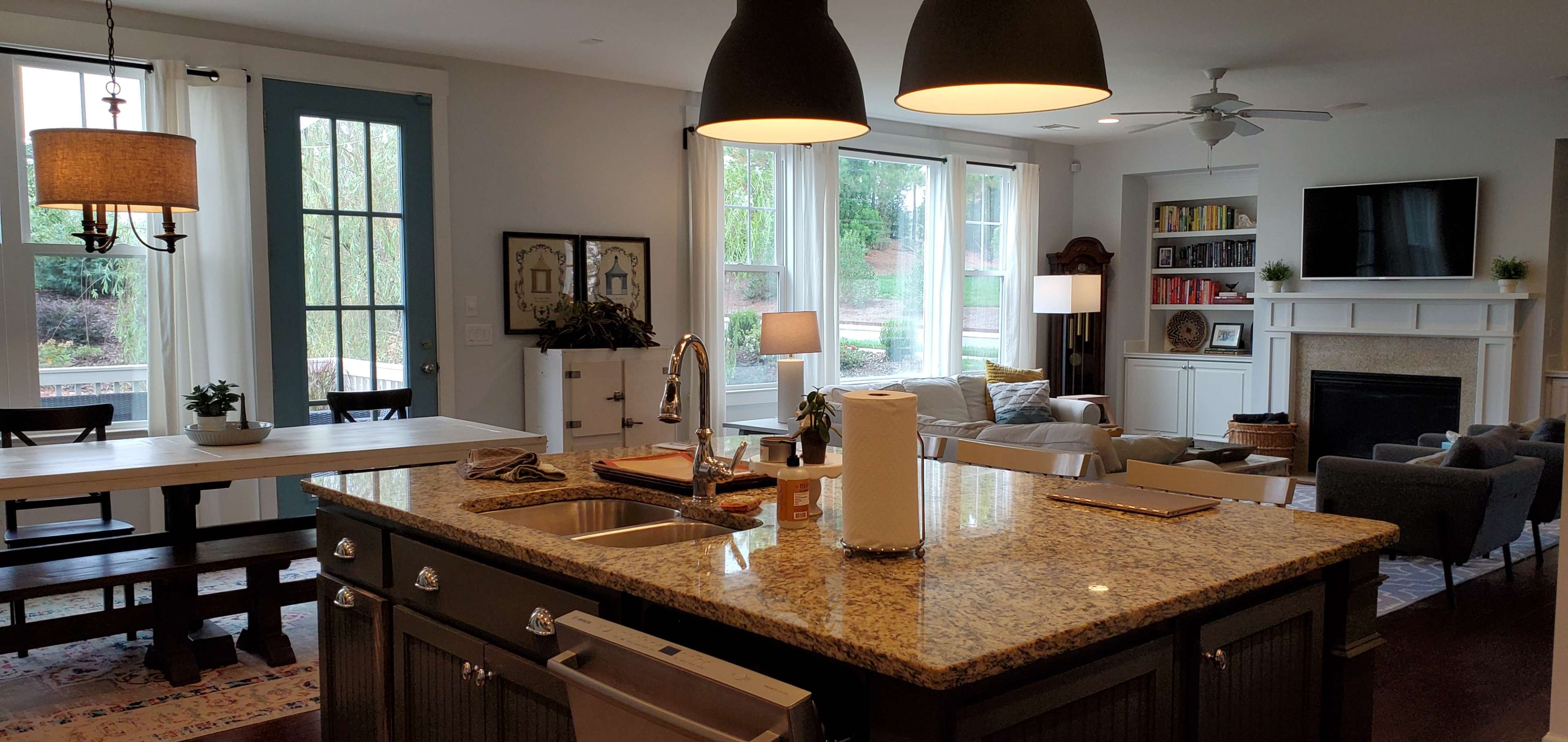 A spacious open-plan kitchen and living area features a large island with a sink, a dining table, and a seating arrangement near a fireplace.