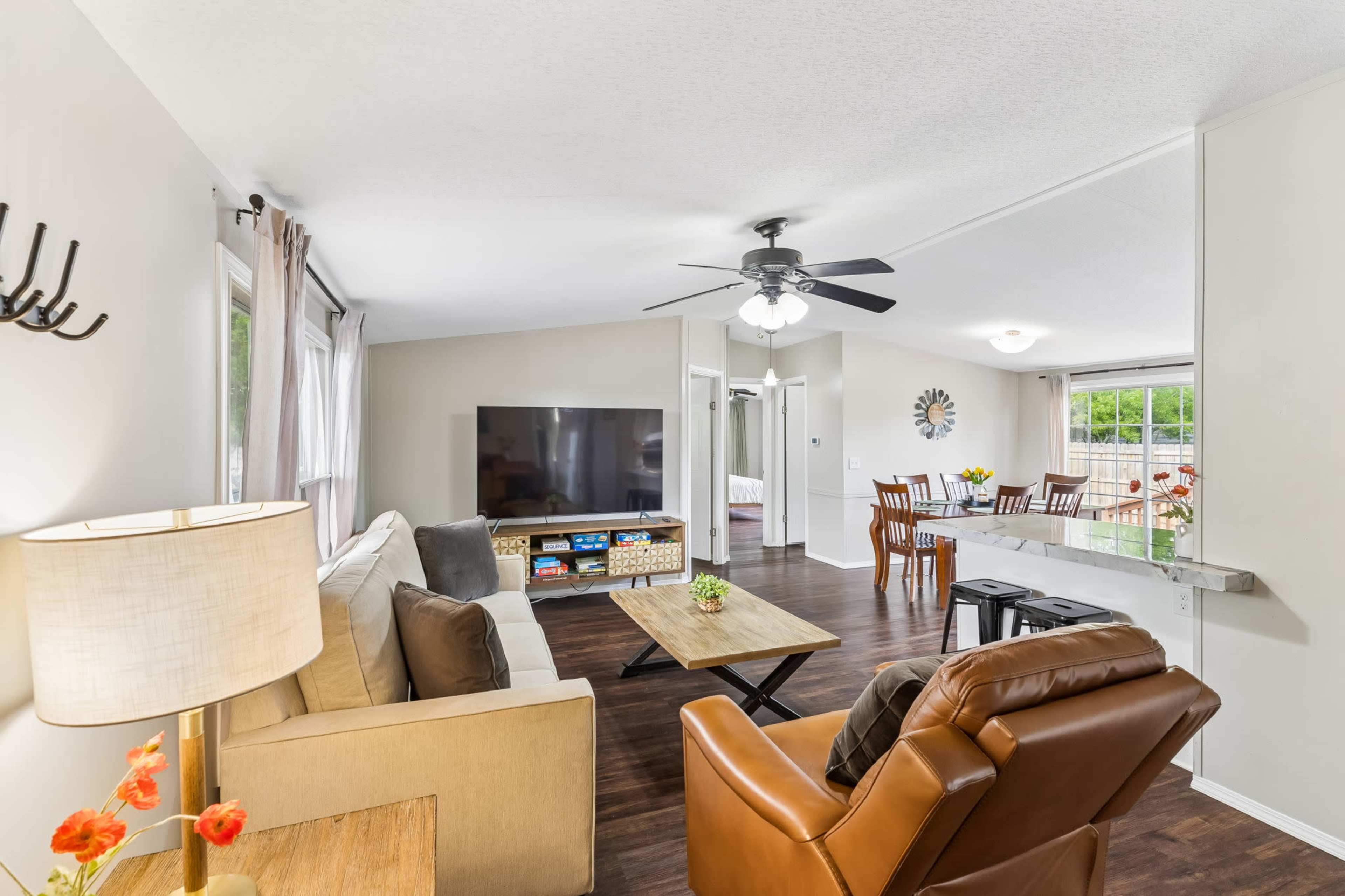 The image shows a living room with a sofa, a coffee table, a television, and a dining area visible in the background.