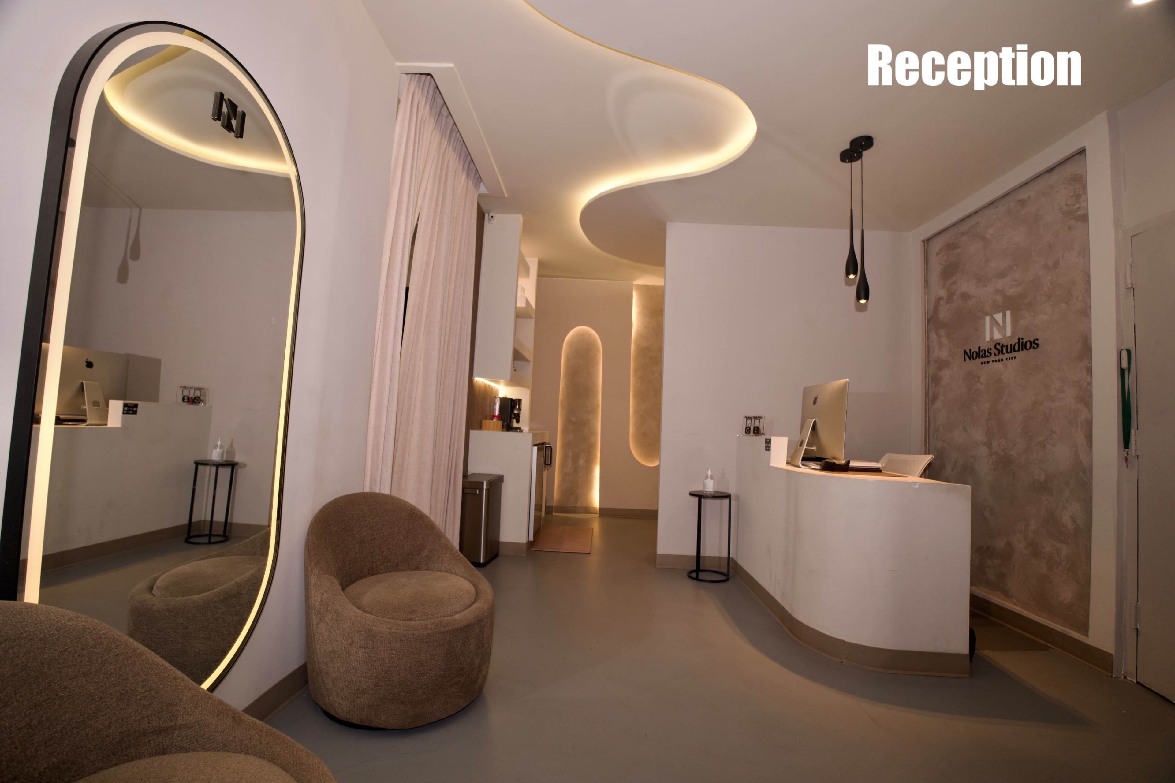 The image shows a modern reception area featuring curved lighting, a front desk, and two round chairs.