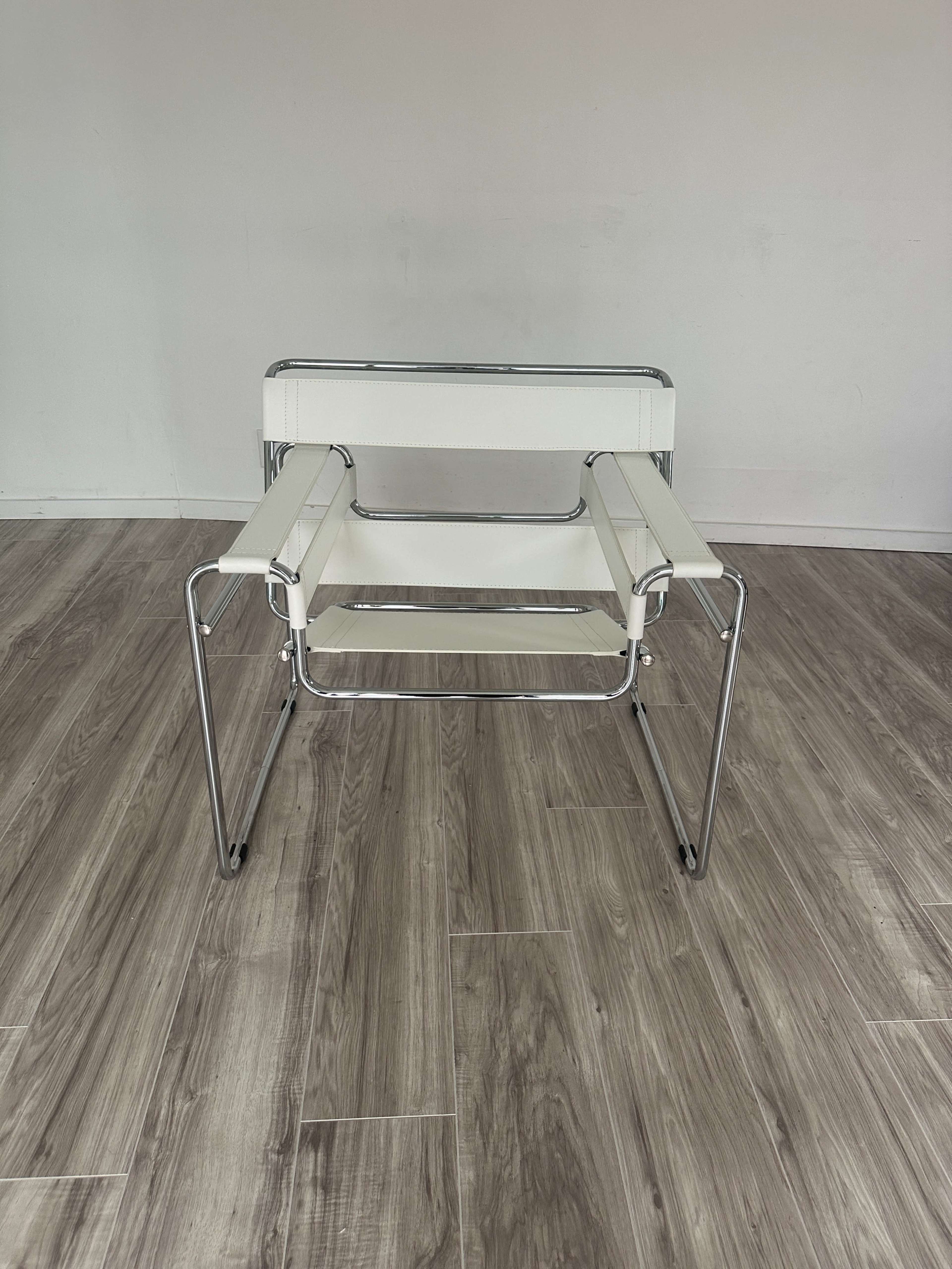 The image shows a modern, minimalist chair with a chrome frame and white leather seats, placed on a wooden floor.