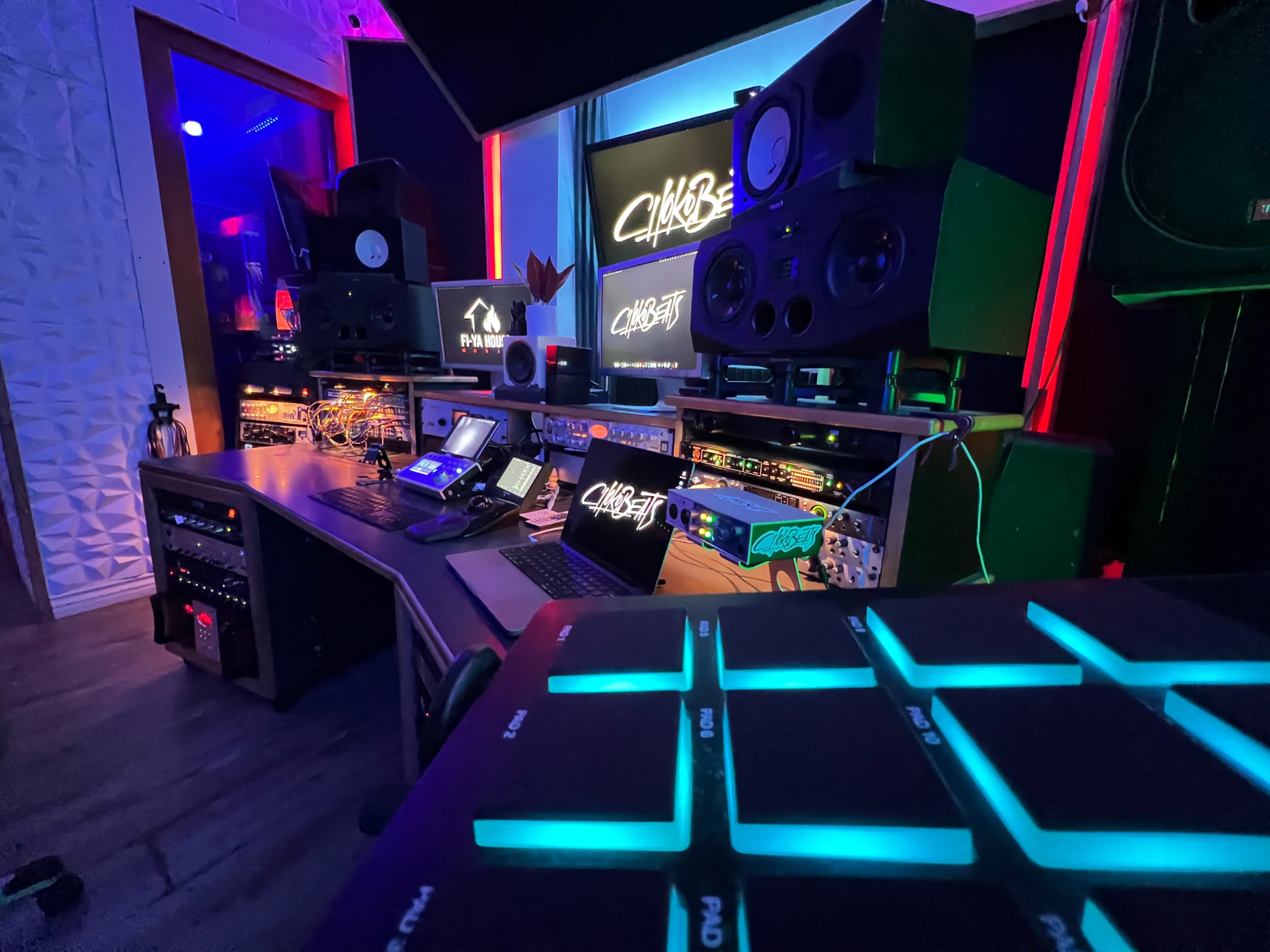 A music production studio features various audio equipment, including speakers, mixing consoles, and colorful lighting.
