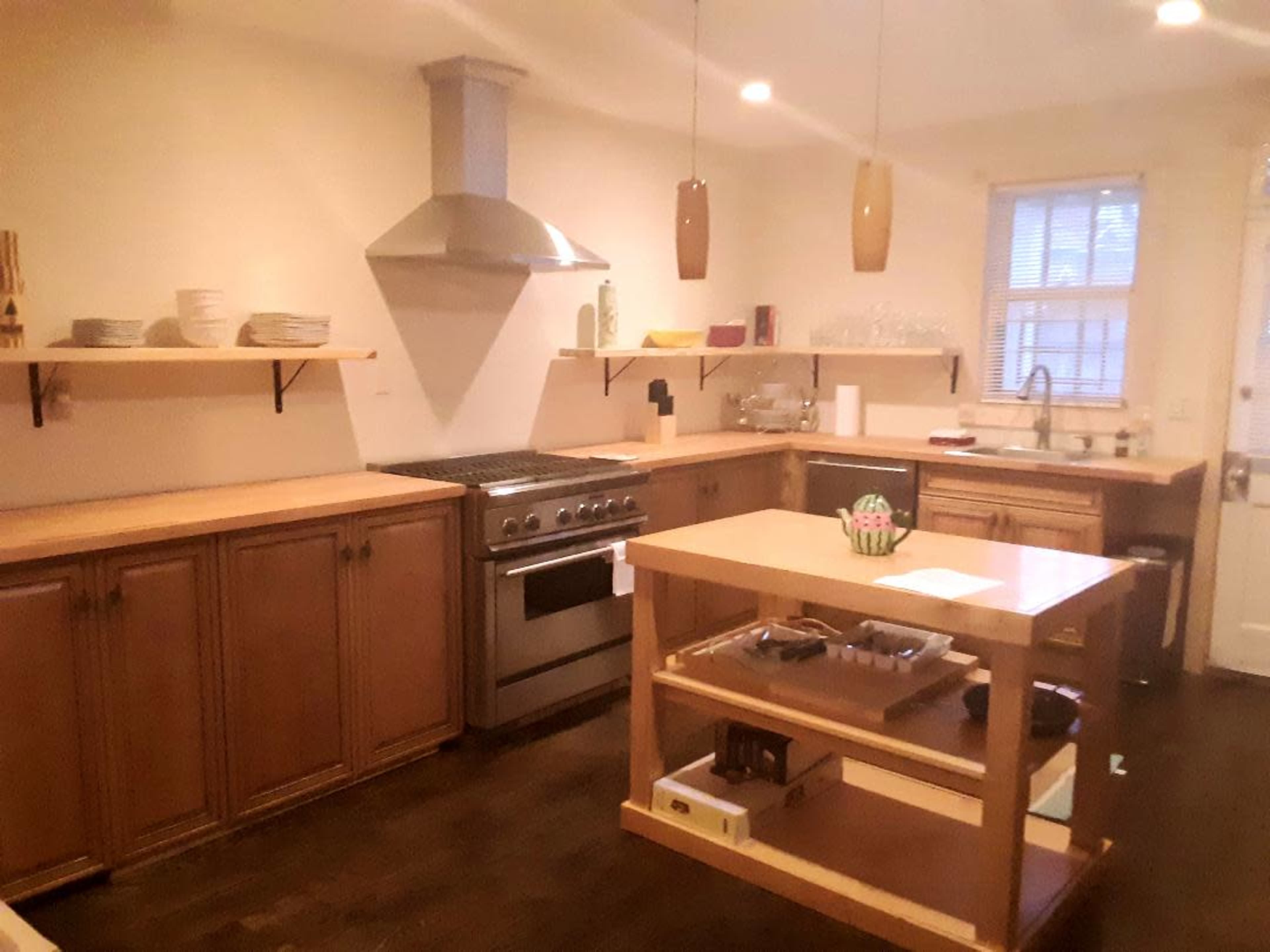 A modern kitchen with wooden cabinets, a stainless steel stove, and an island with open shelving.