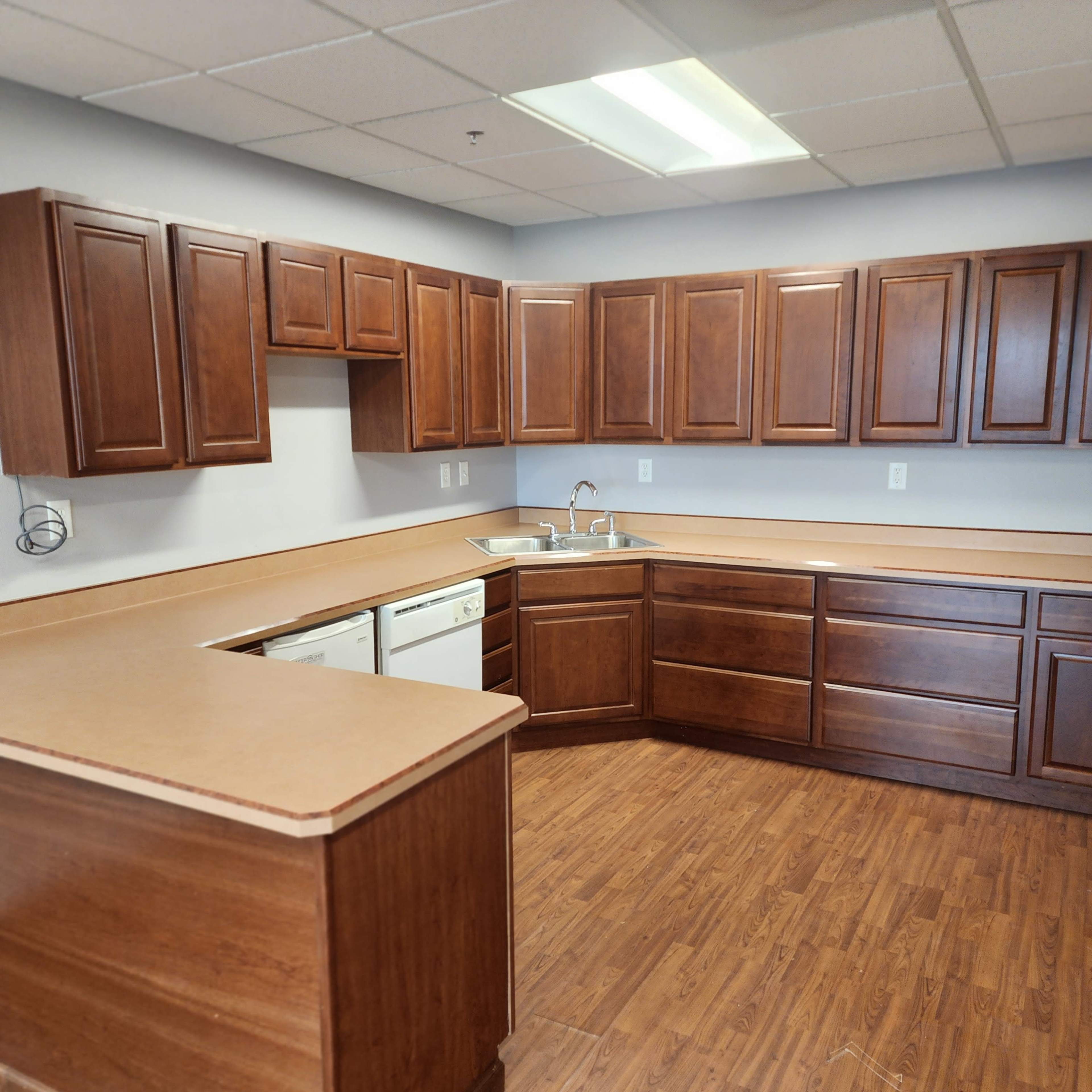 A spacious kitchen with wooden cabinets, a countertop, and appliances including a sink and dishwasher.