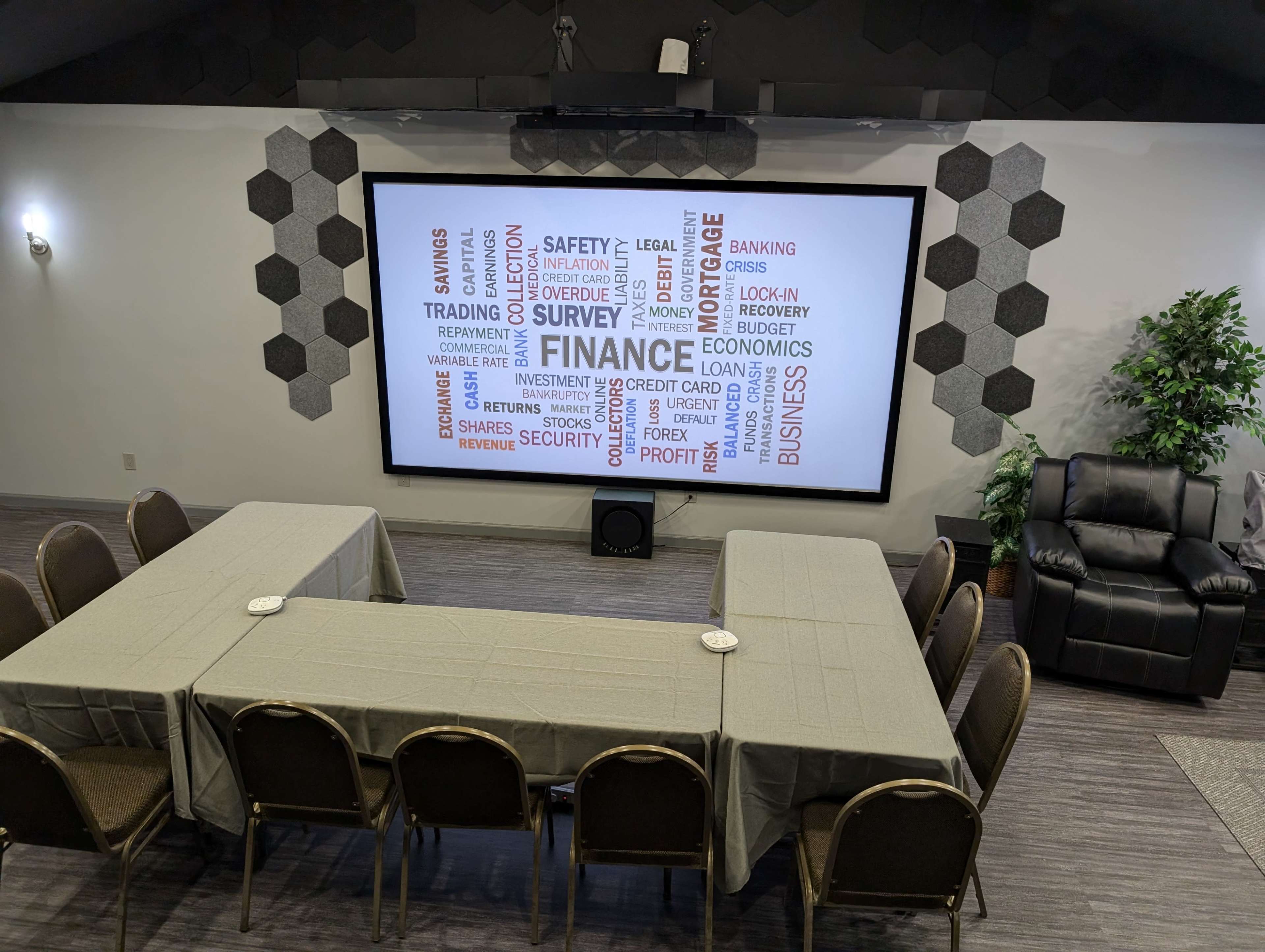 A conference room features a large screen displaying finance-related terms, surrounded by tables set up for a meeting.