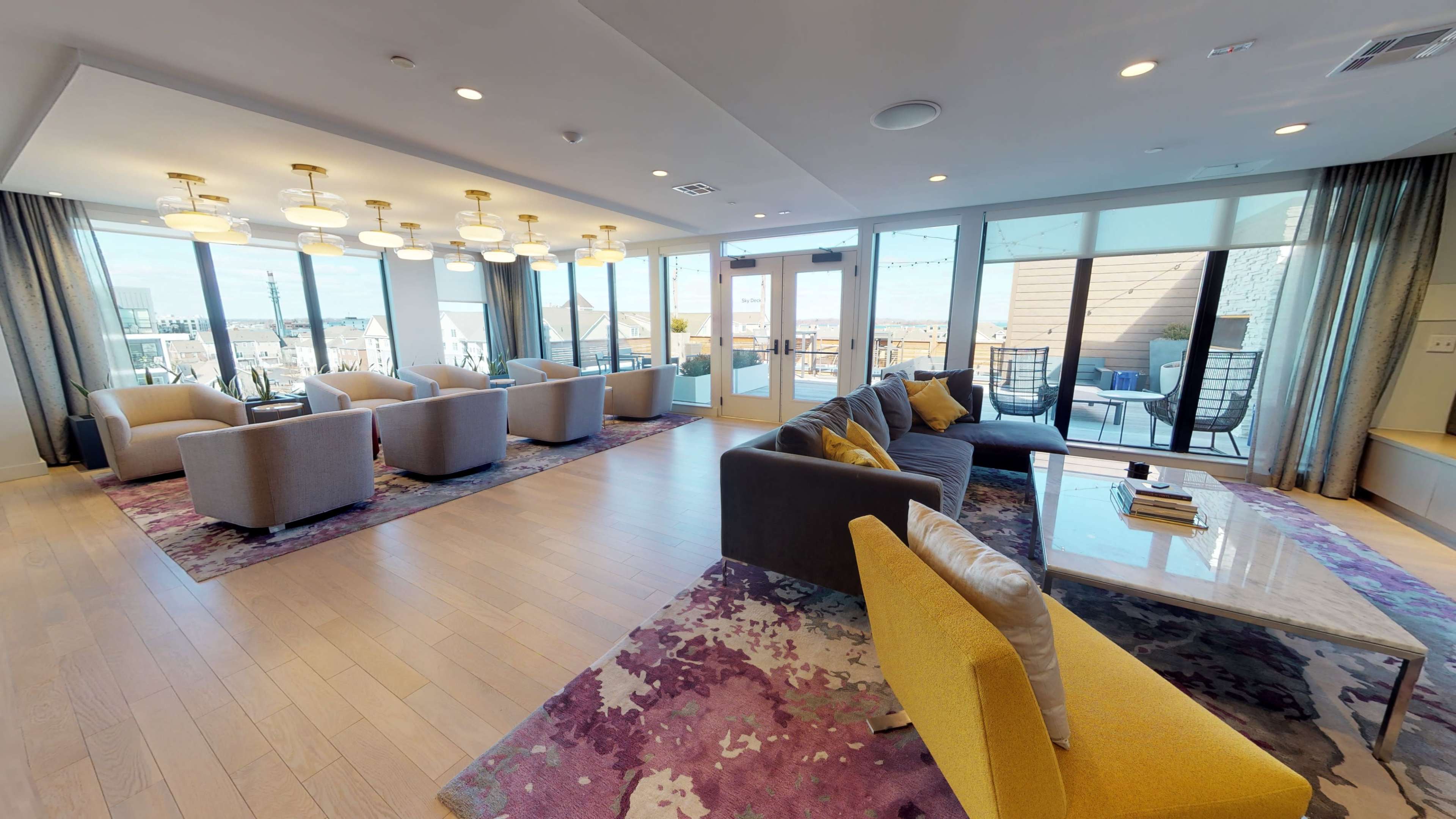A modern lounge area with several seating arrangements, large windows, and a view of the outdoors.