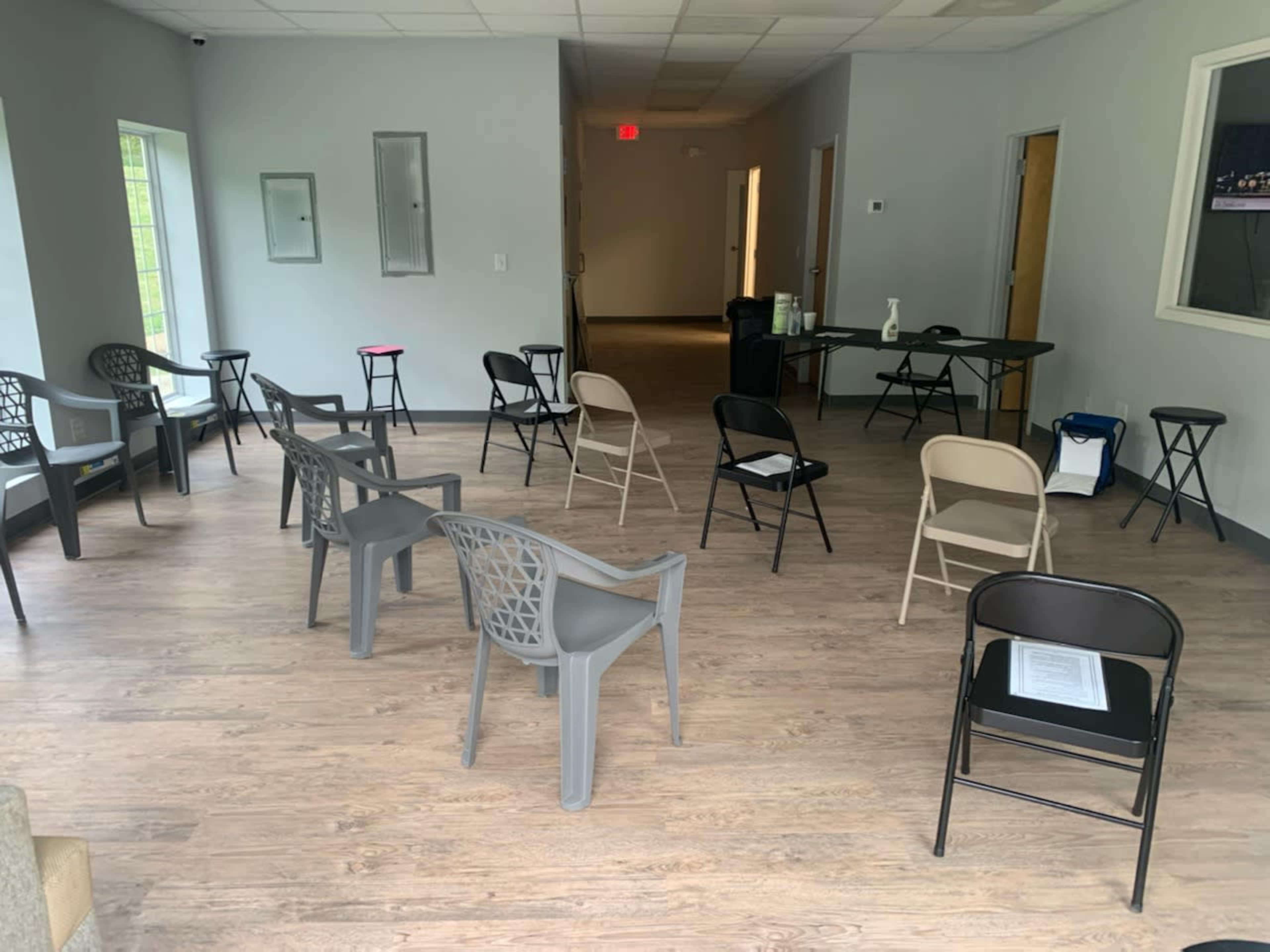The room contains several empty chairs arranged around a central space, with a table and a few items against the walls.