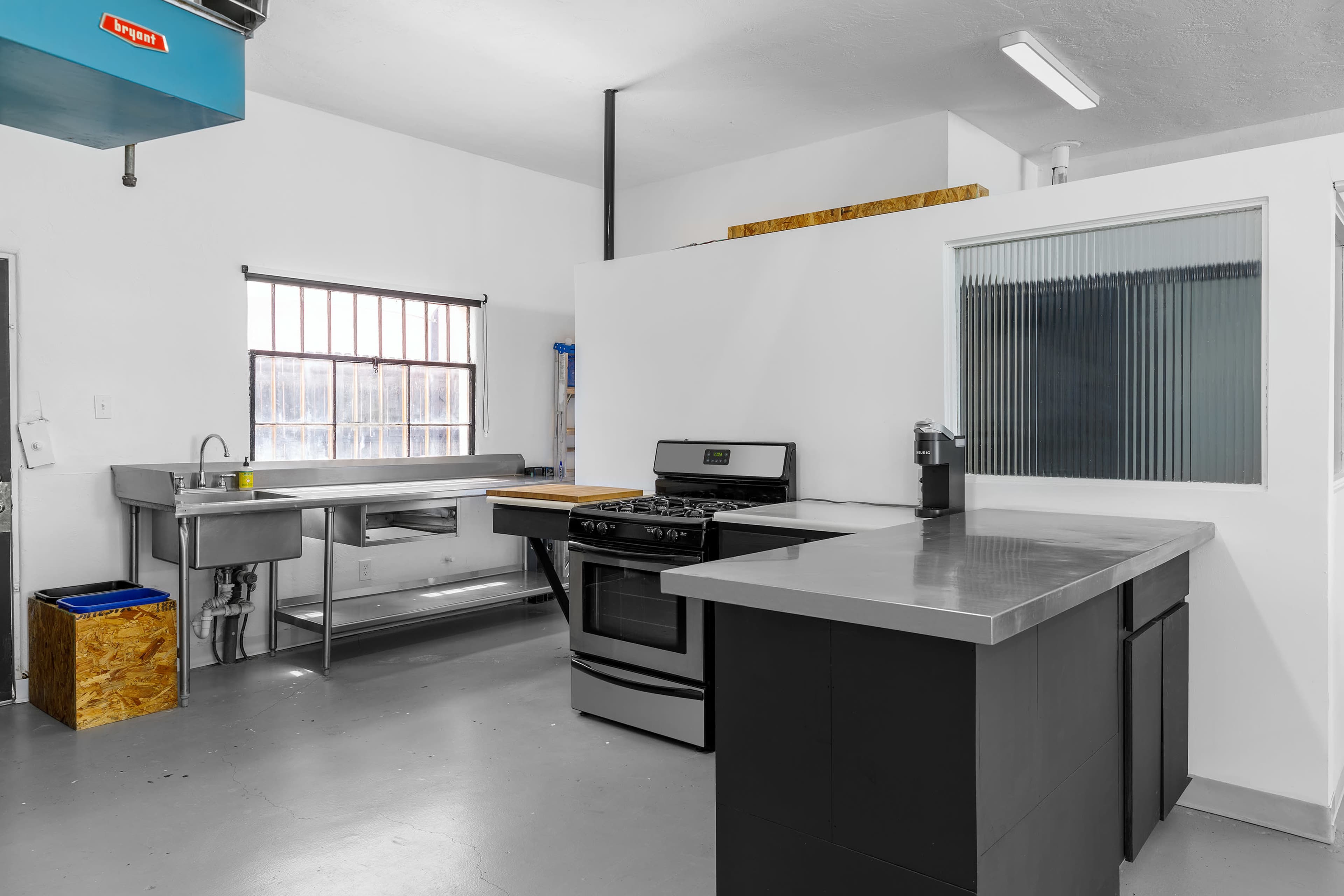 A modern kitchen with a stainless steel sink, a gas stove, and a minimalistic island countertop.