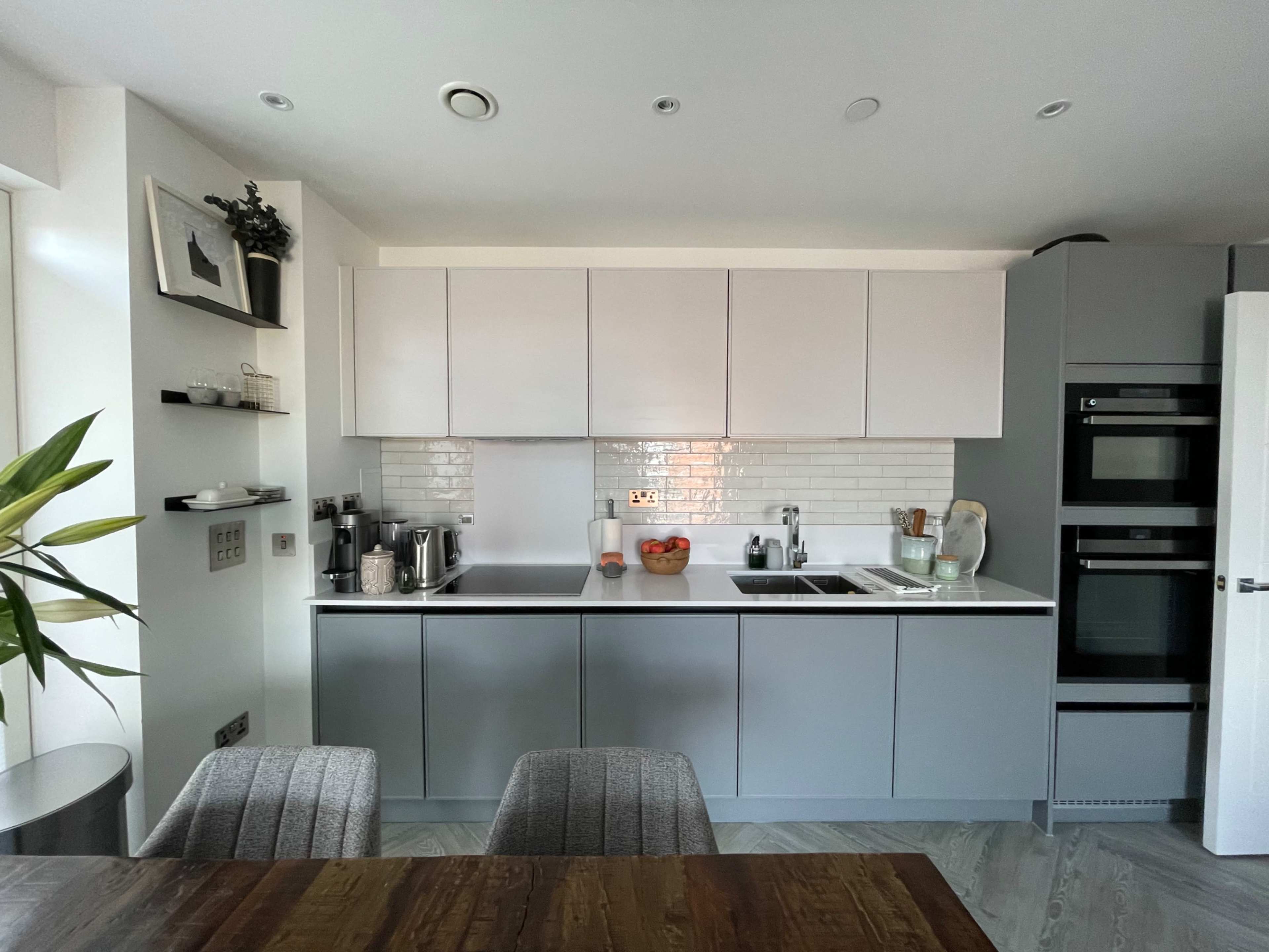 The image shows a modern kitchen with sleek cabinets, a clean countertop, and built-in appliances.
