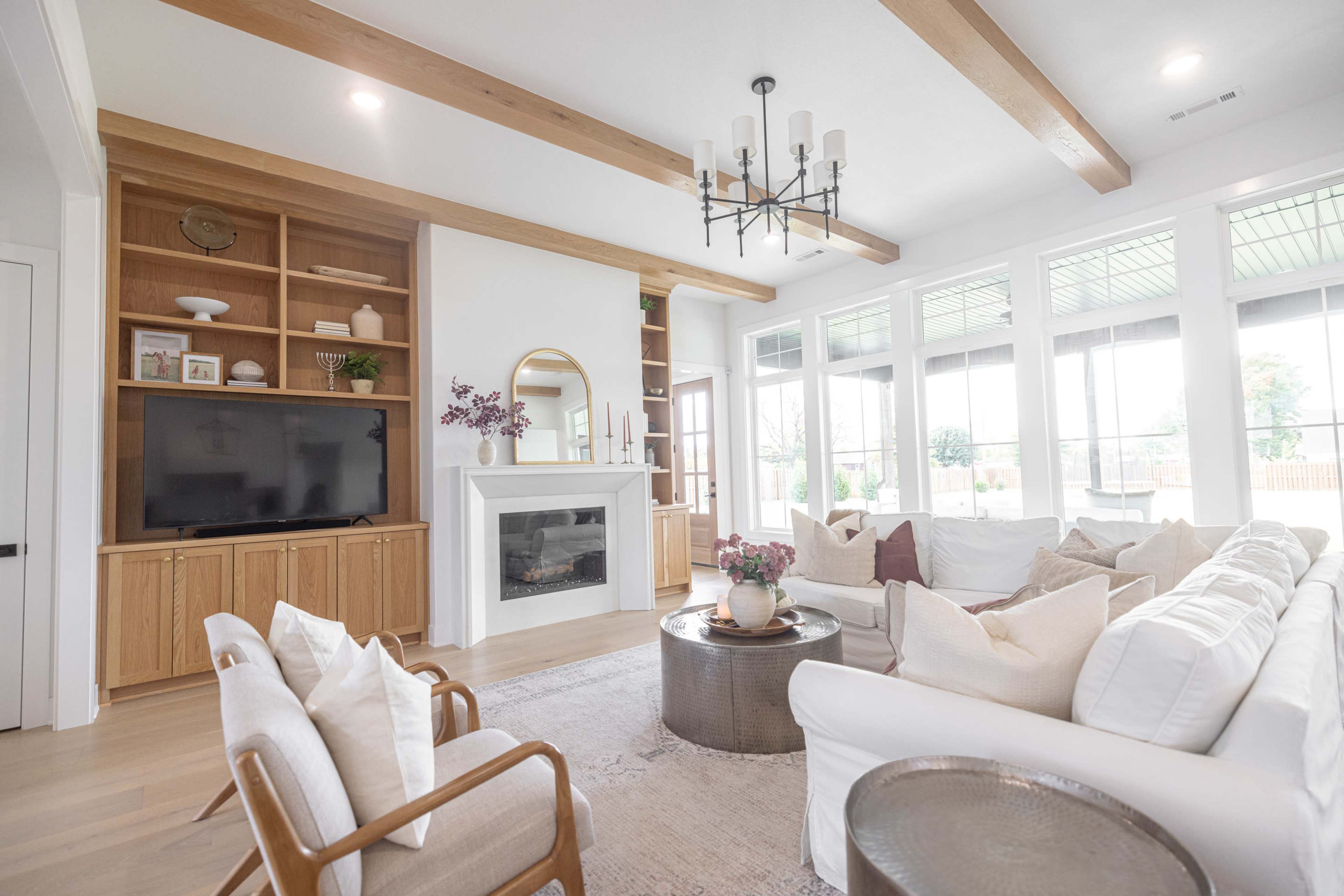 A modern living room with a fireplace, built-in shelving, large windows, and a comfortable furniture arrangement.