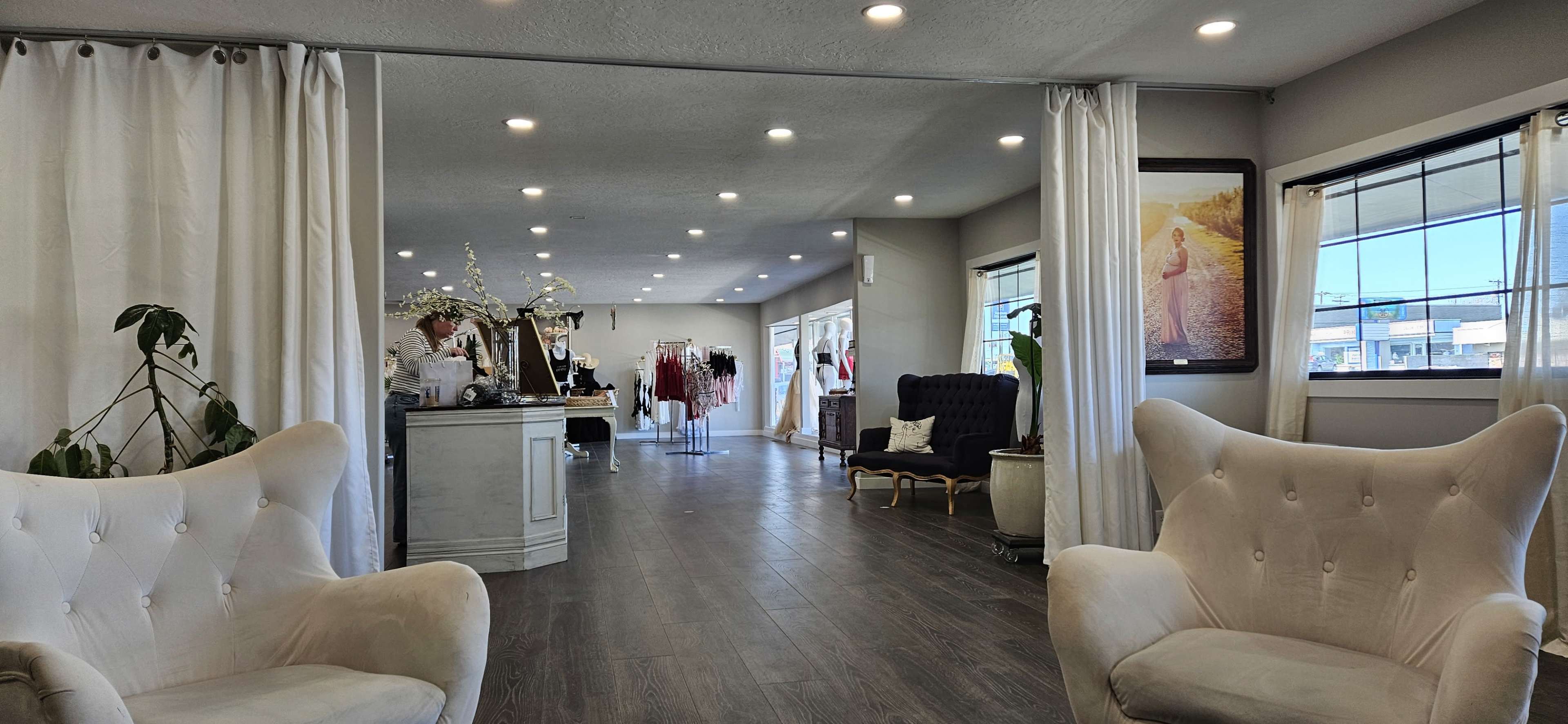 A spacious boutique interior with two armchairs at the entrance, a reception area, and various clothing displays in the background.