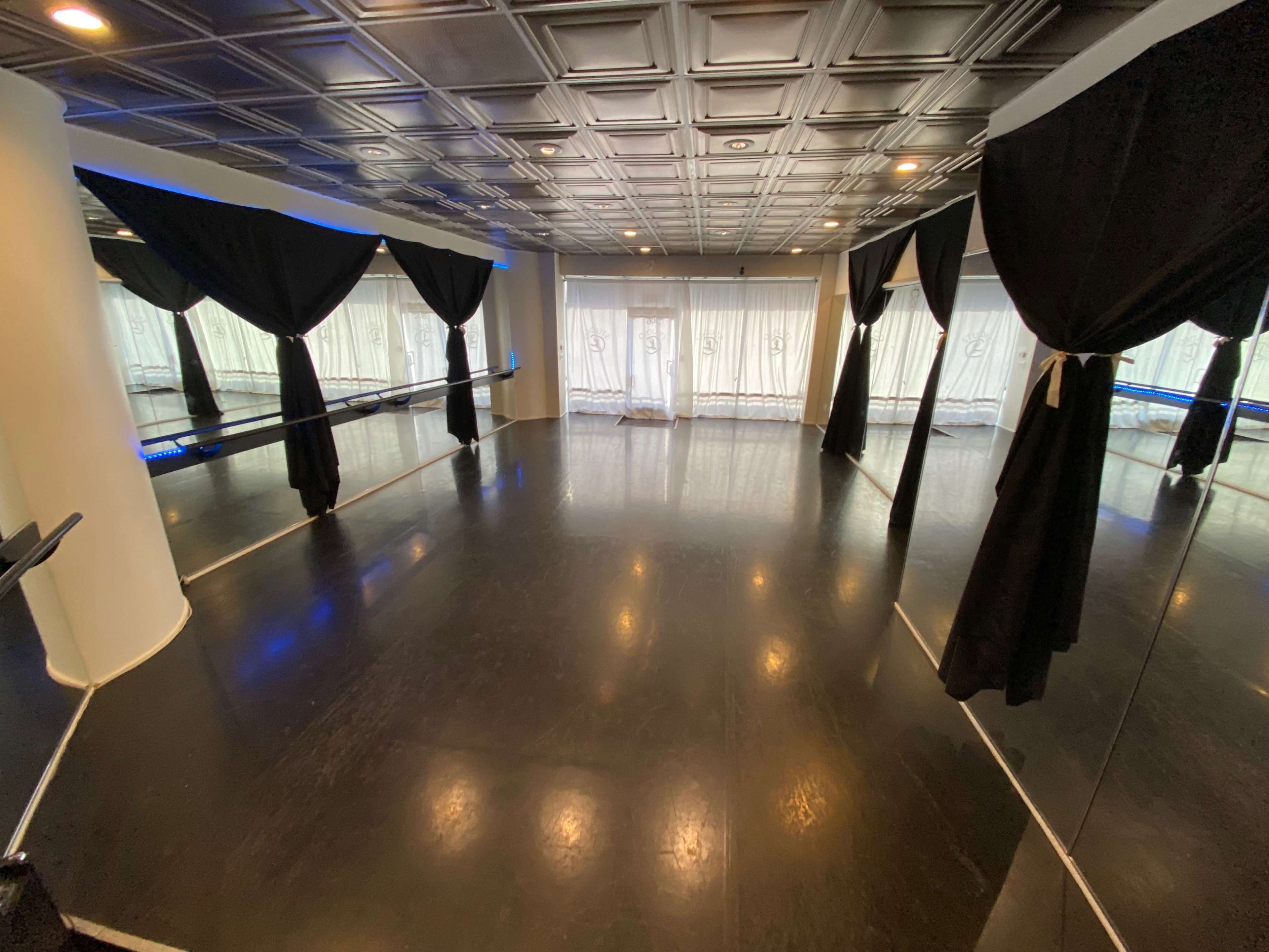 The room features black flooring and tall mirrors, with flowing black curtains draping from the tall ceiling.