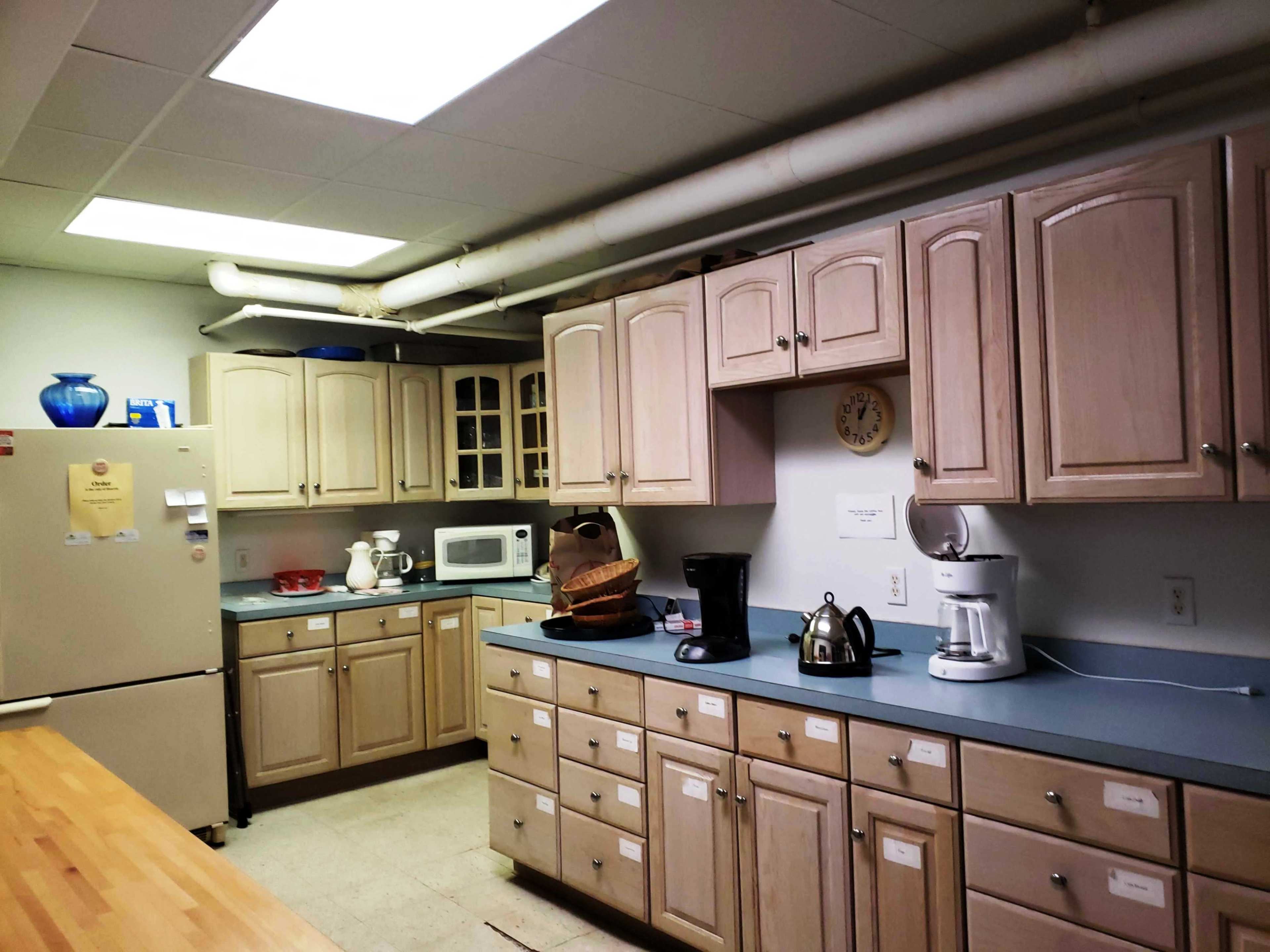 The kitchen features light-colored cabinetry, a microwave, a coffee maker, and various appliances arranged on blue countertops.