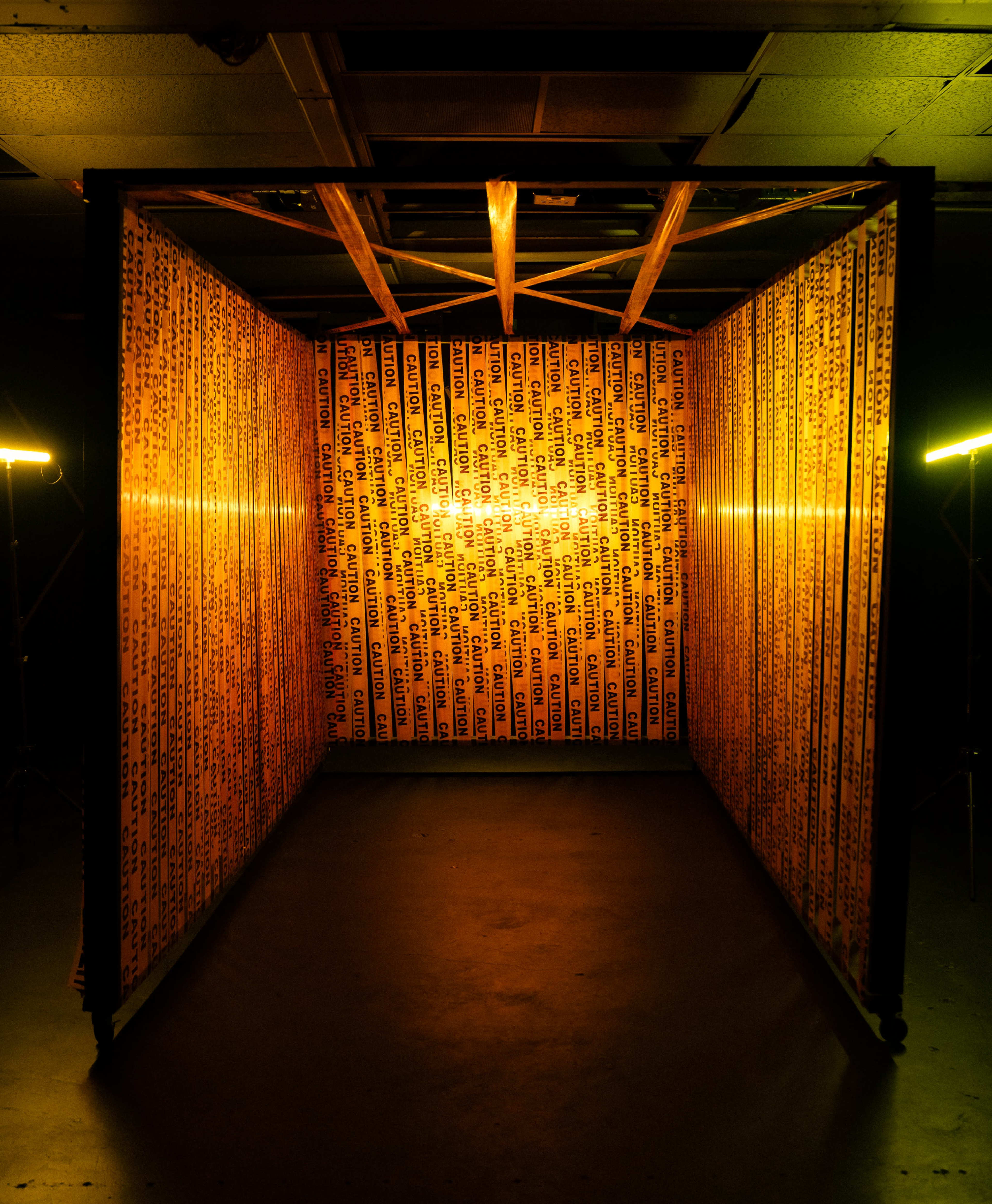 A small room is illuminated with warm yellow lighting and lined with patterned text on the walls.