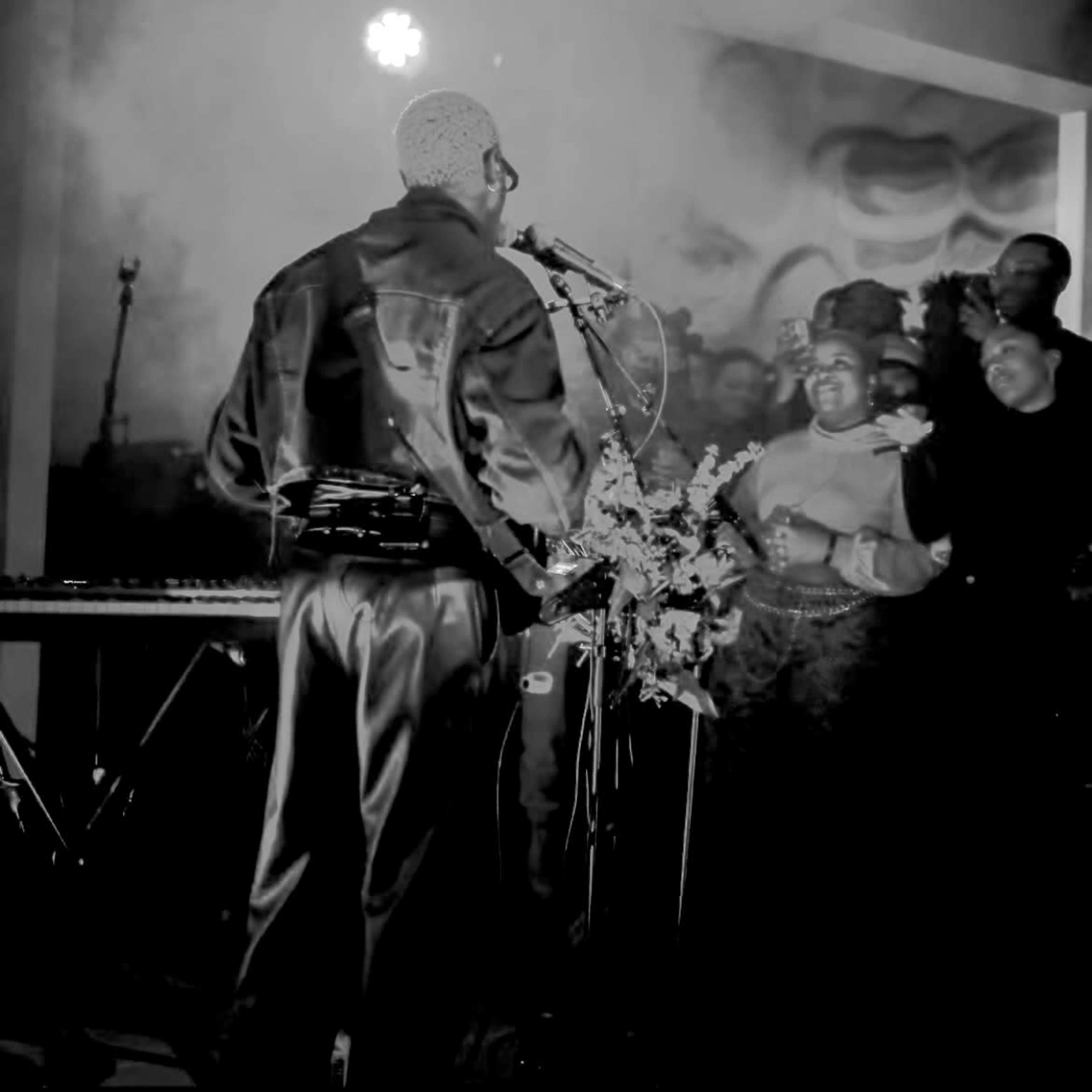 A musician performs on stage in front of an audience, with smoke and dim lighting enhancing the atmosphere.