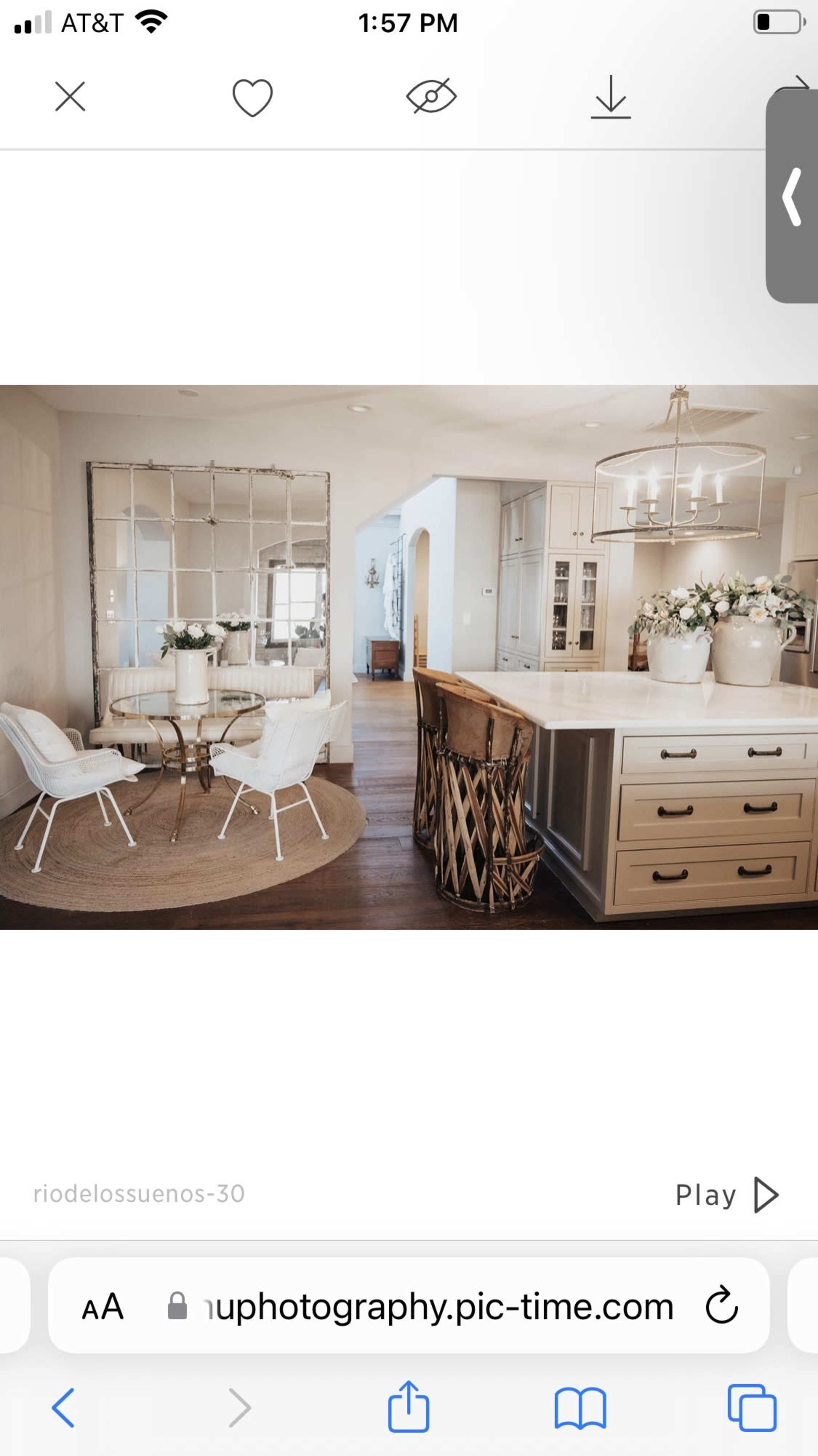 A modern kitchen features a large island with a dining area to the side, complemented by a round rug and reflective wall decor.