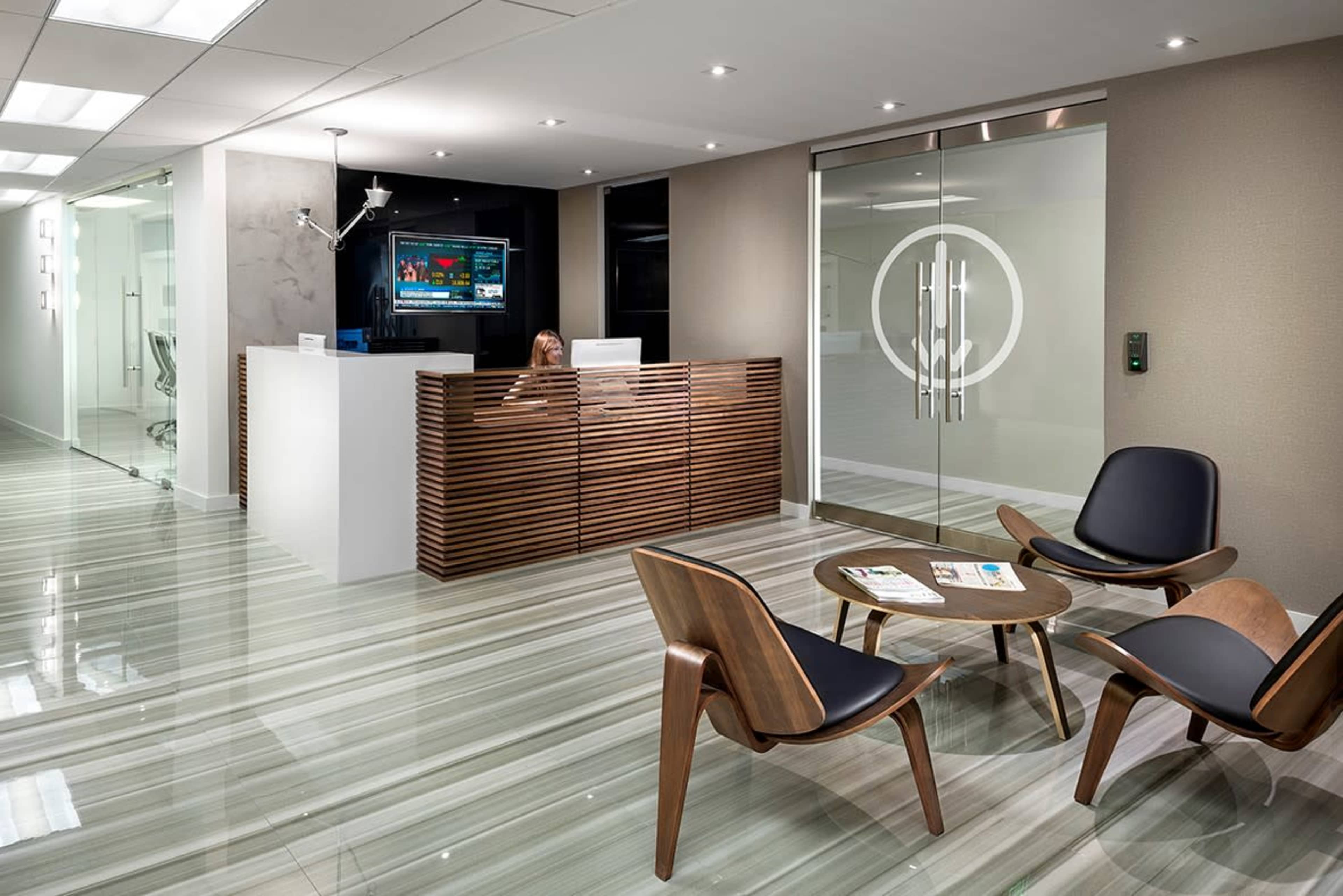 A modern reception area features a sleek front desk, contemporary seating, and large glass doors.