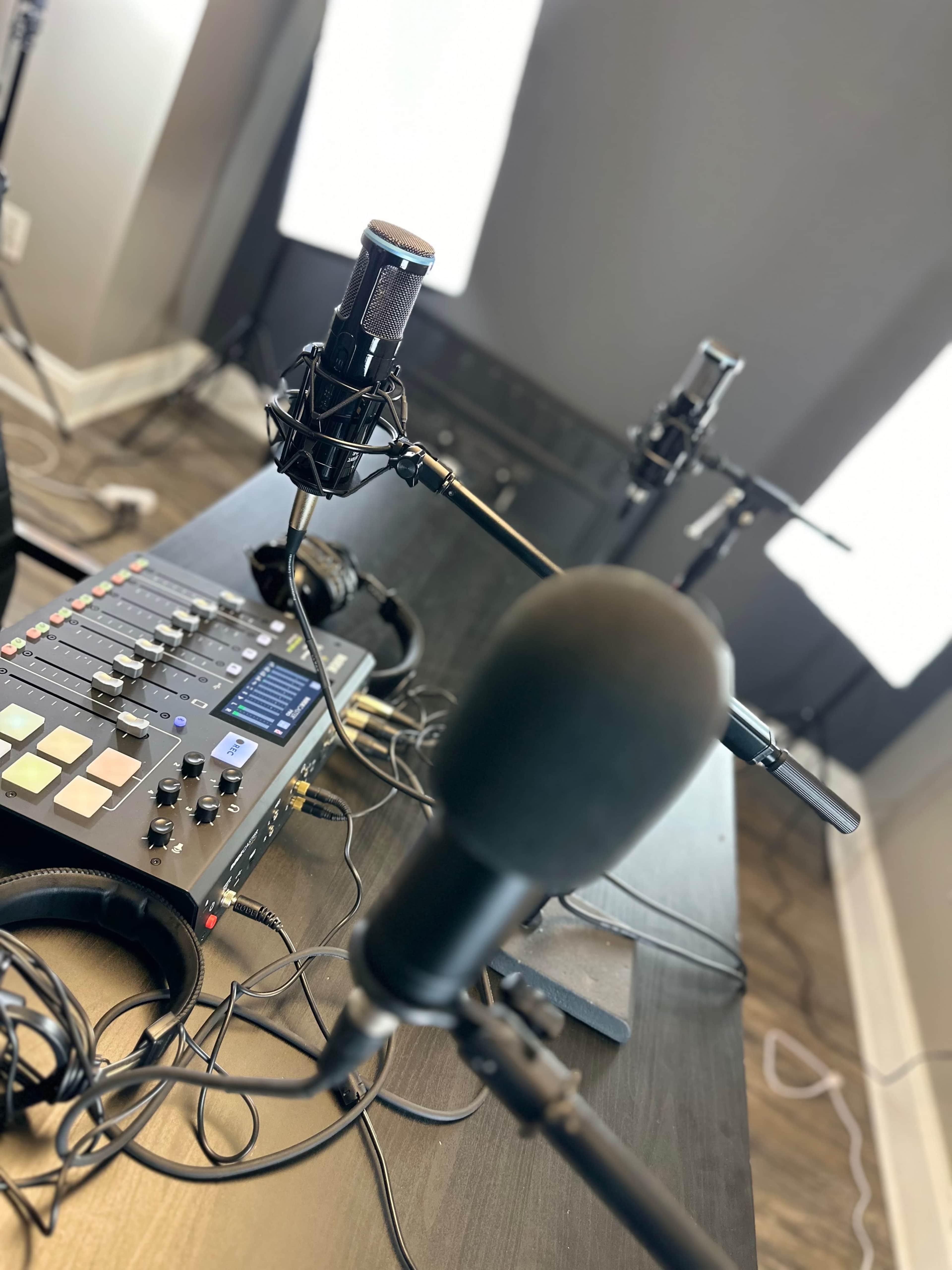 A recording setup featuring multiple microphones and an audio mixer on a table in a well-lit room.