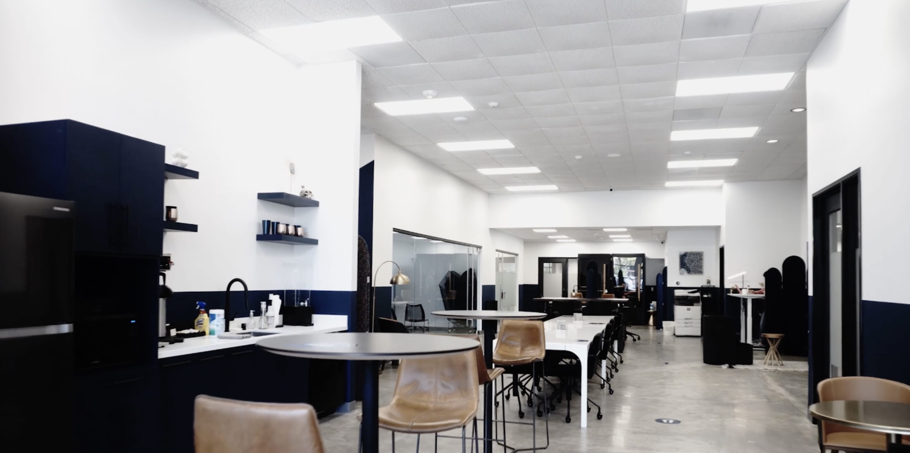 A modern salon interior with a spacious layout, featuring a reception area, styling stations, and a mix of furniture in neutral colors.