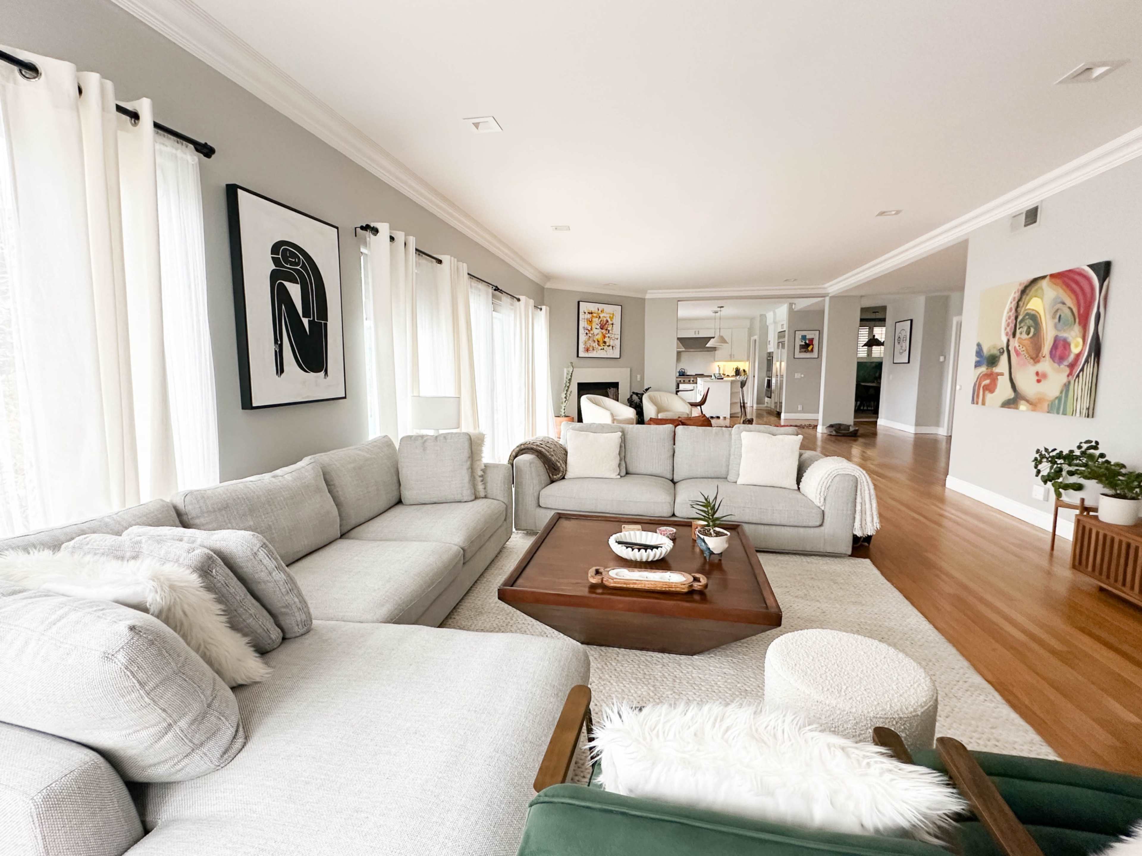 The living room features a large sectional sofa, a wooden coffee table, and various artworks on the walls.