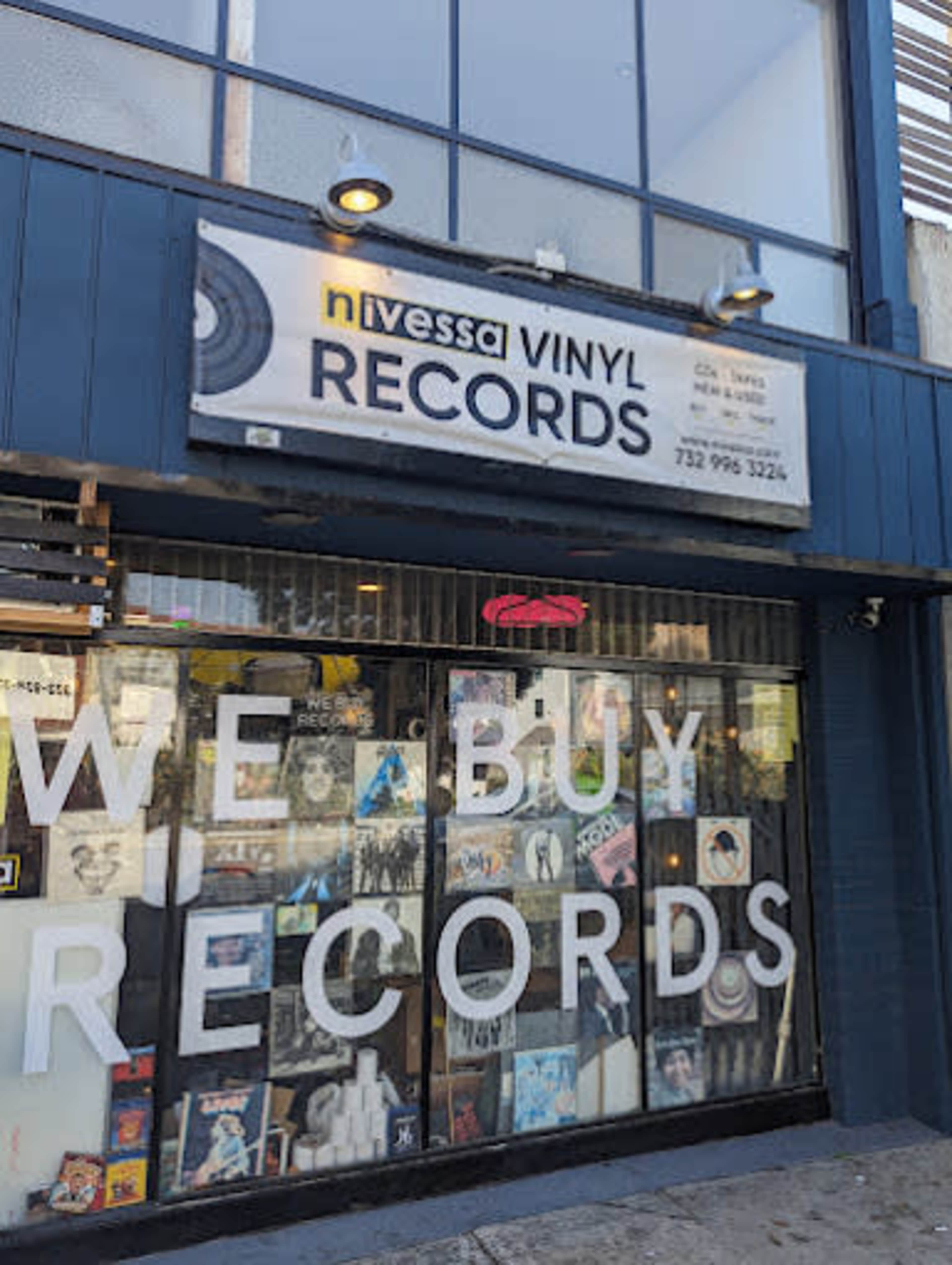 The image shows a storefront of a vinyl records shop with large signage and a window displaying various album covers.