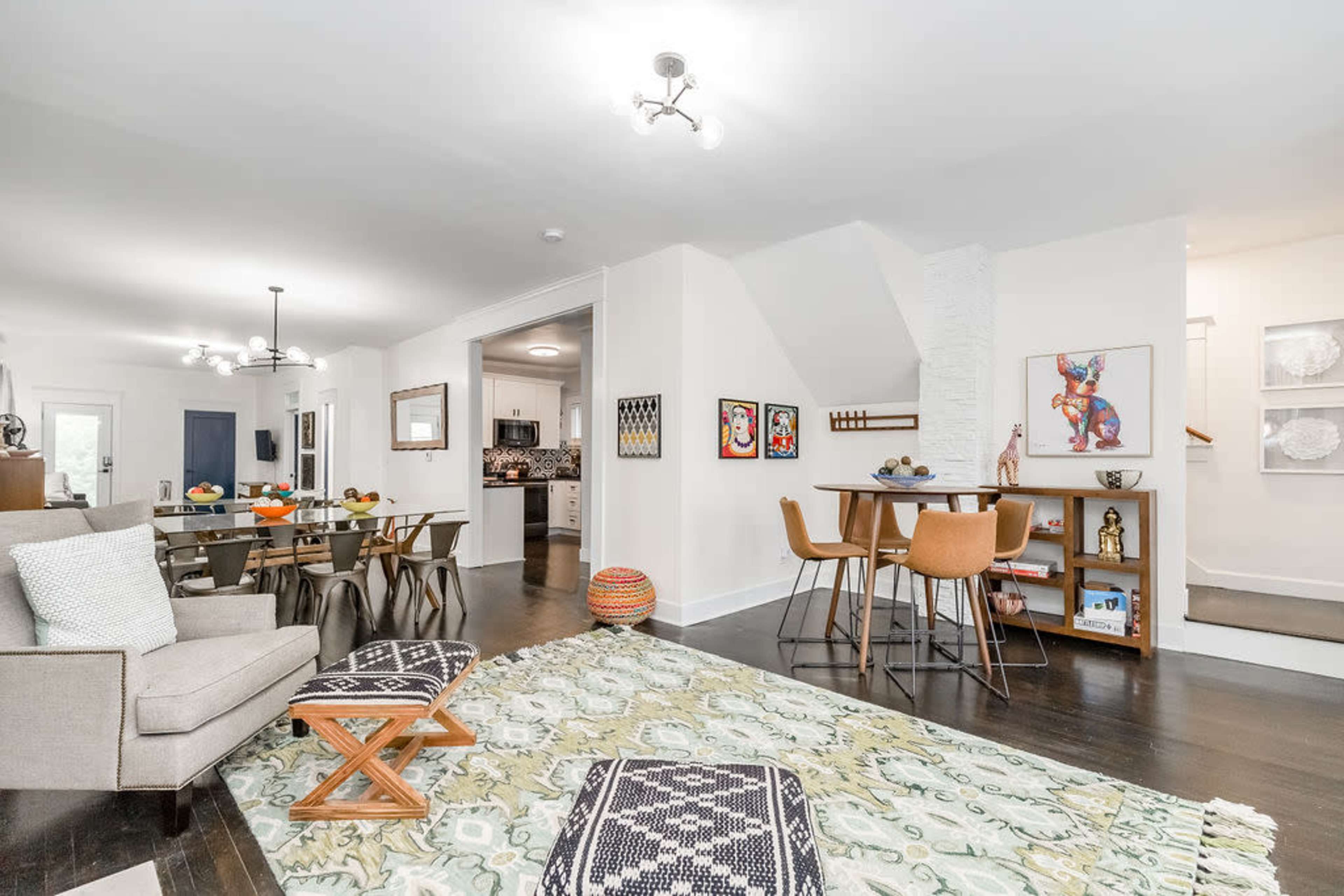 A brightly lit open-plan living space featuring a dining area, a cozy living room, and a modern kitchen in the background.
