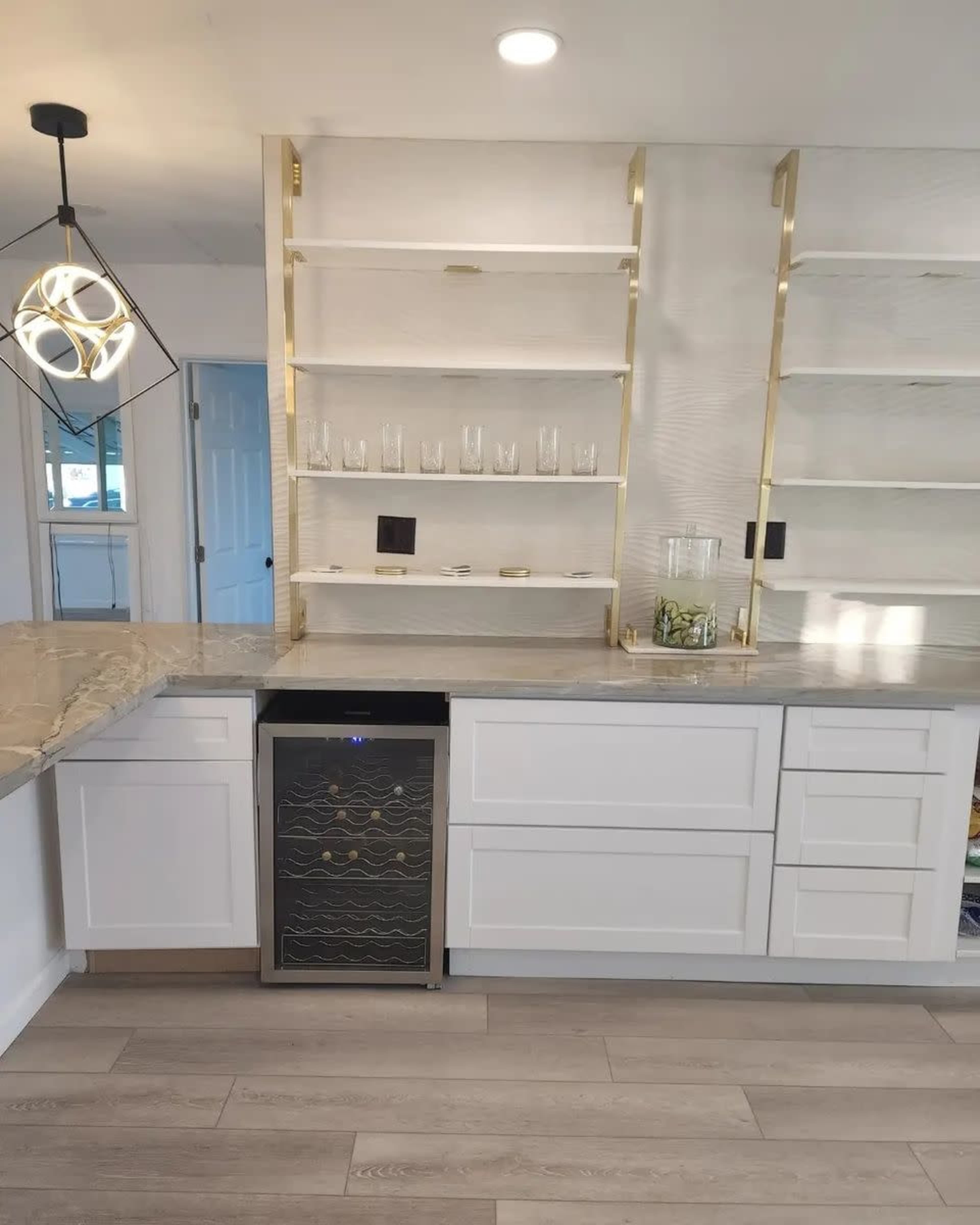 A modern kitchen with white cabinetry, open shelving, a granite countertop, and a wine cooler under the counter.