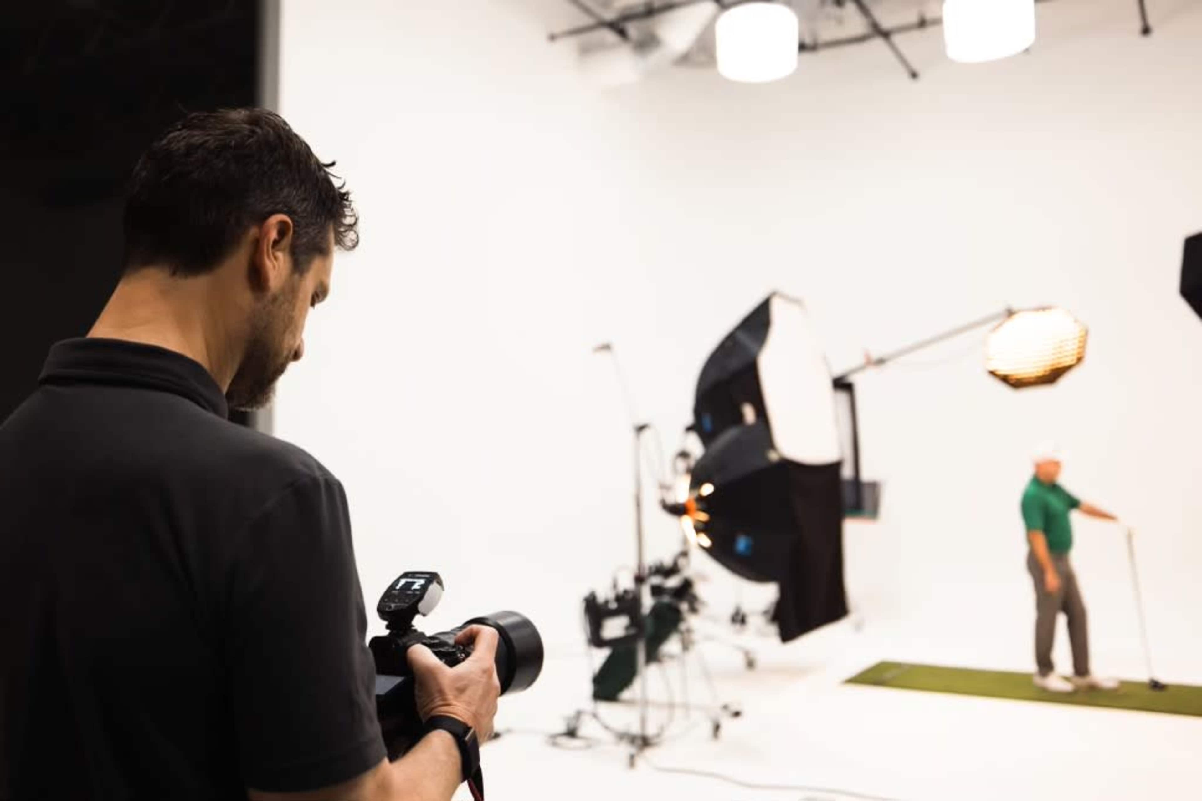 A photographer captures a golfer posing in a studio with multiple lighting setups.