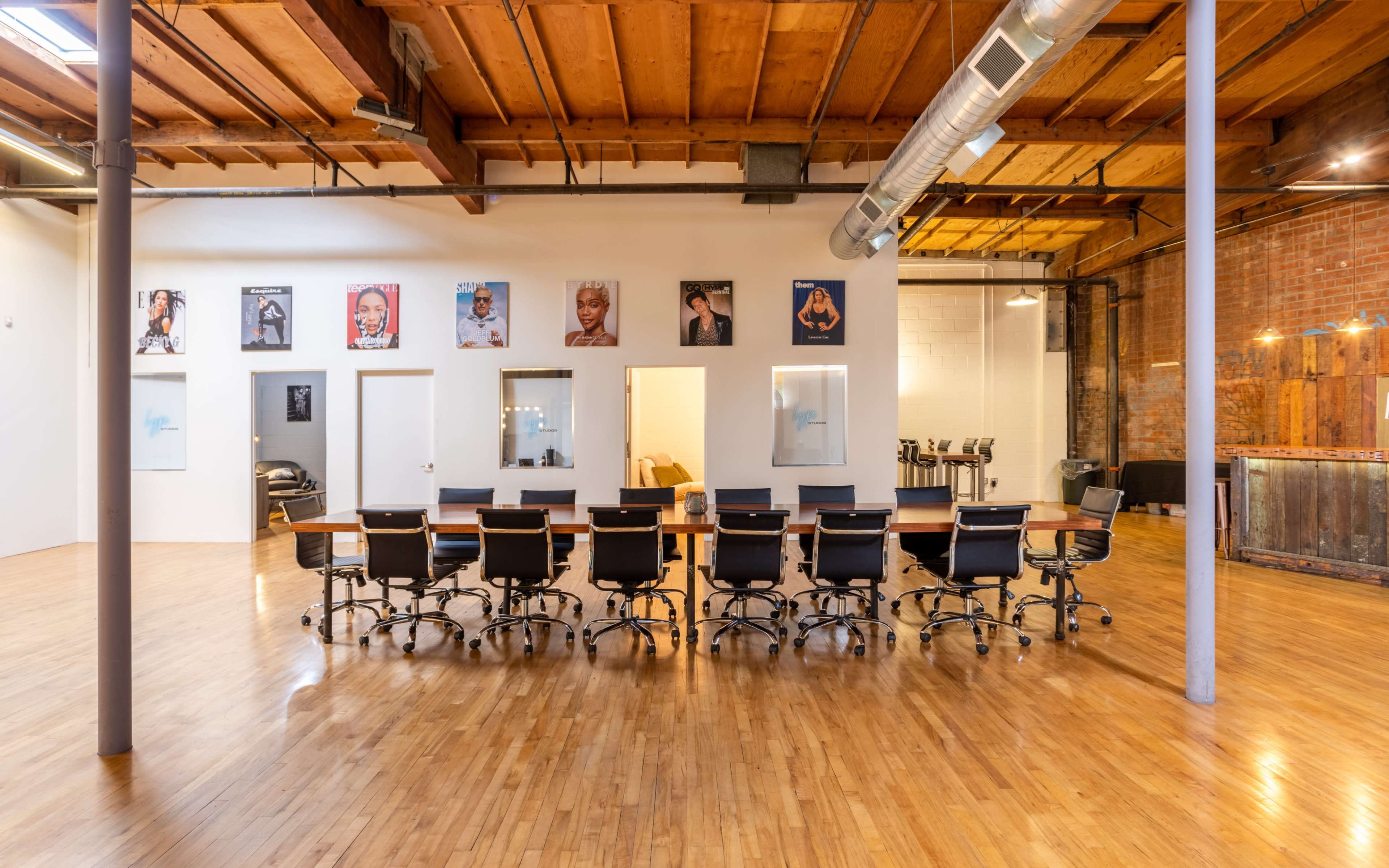 The image shows a spacious office area with a long conference table and various framed portraits hanging on the walls.