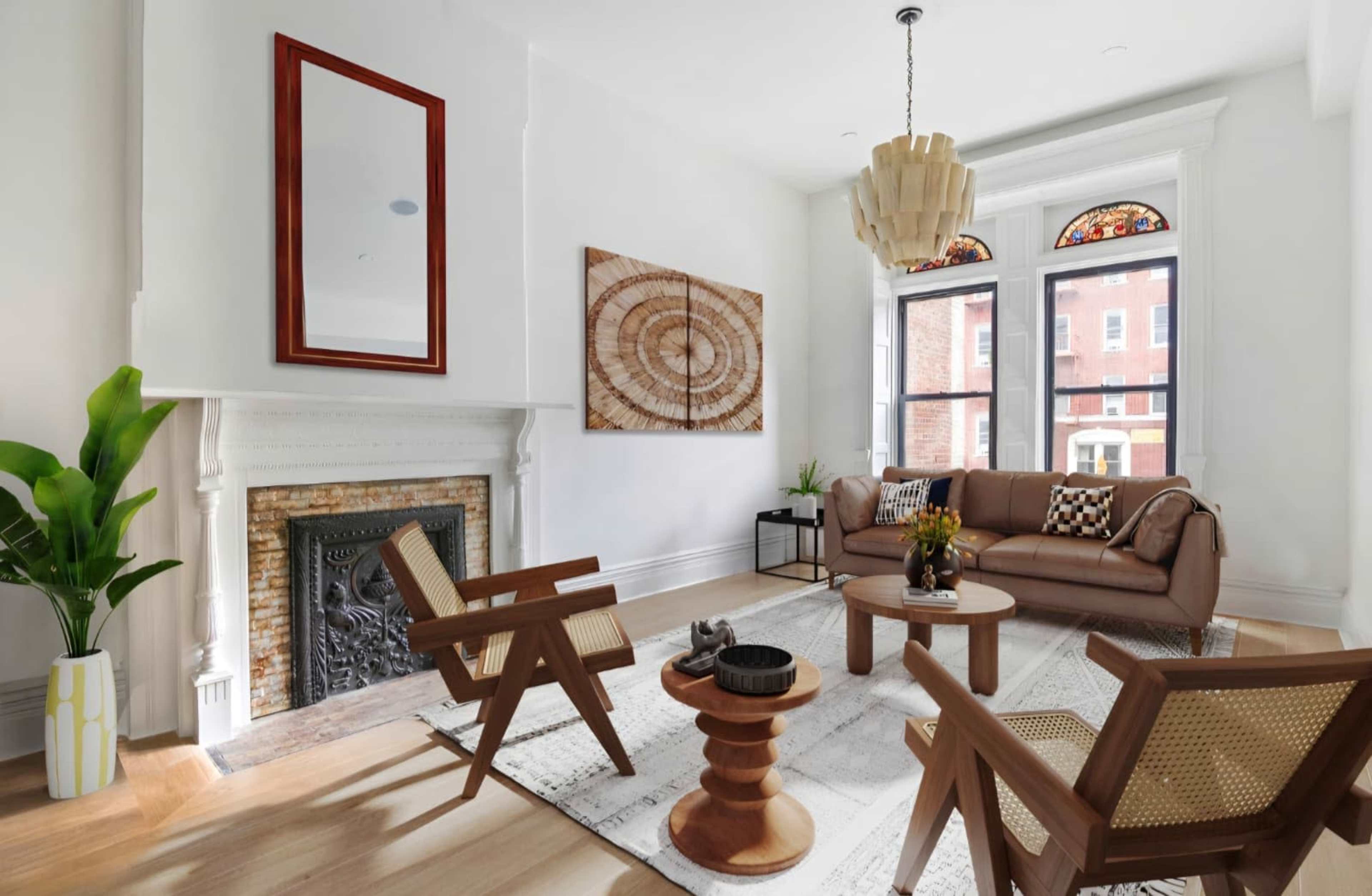 The image shows a modern living room with a brown sofa, wooden chairs, a round coffee table, and large windows with decorative glass.