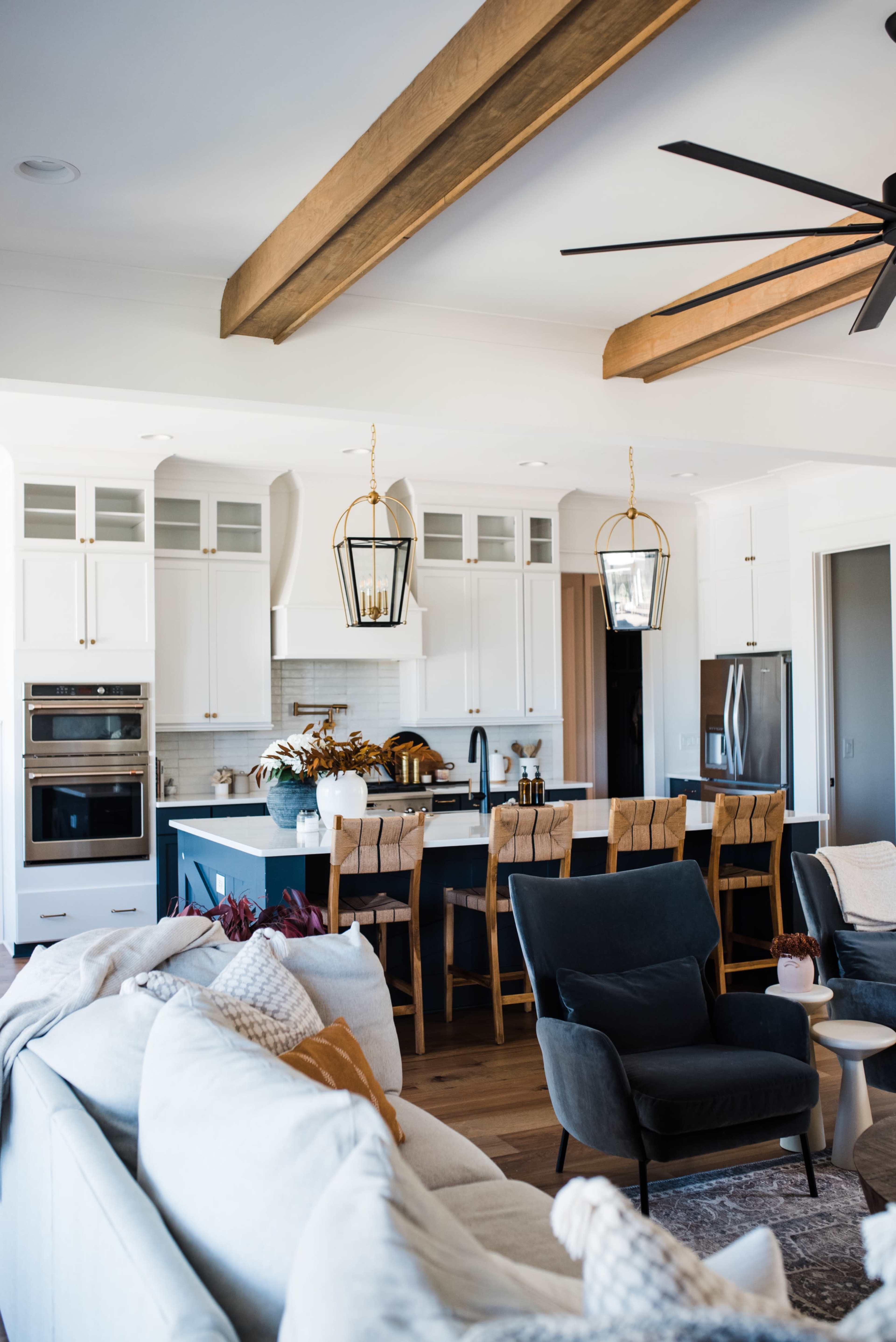 A modern kitchen featuring stainless steel appliances, white cabinetry, a large island with bar seating, and natural wood accents.