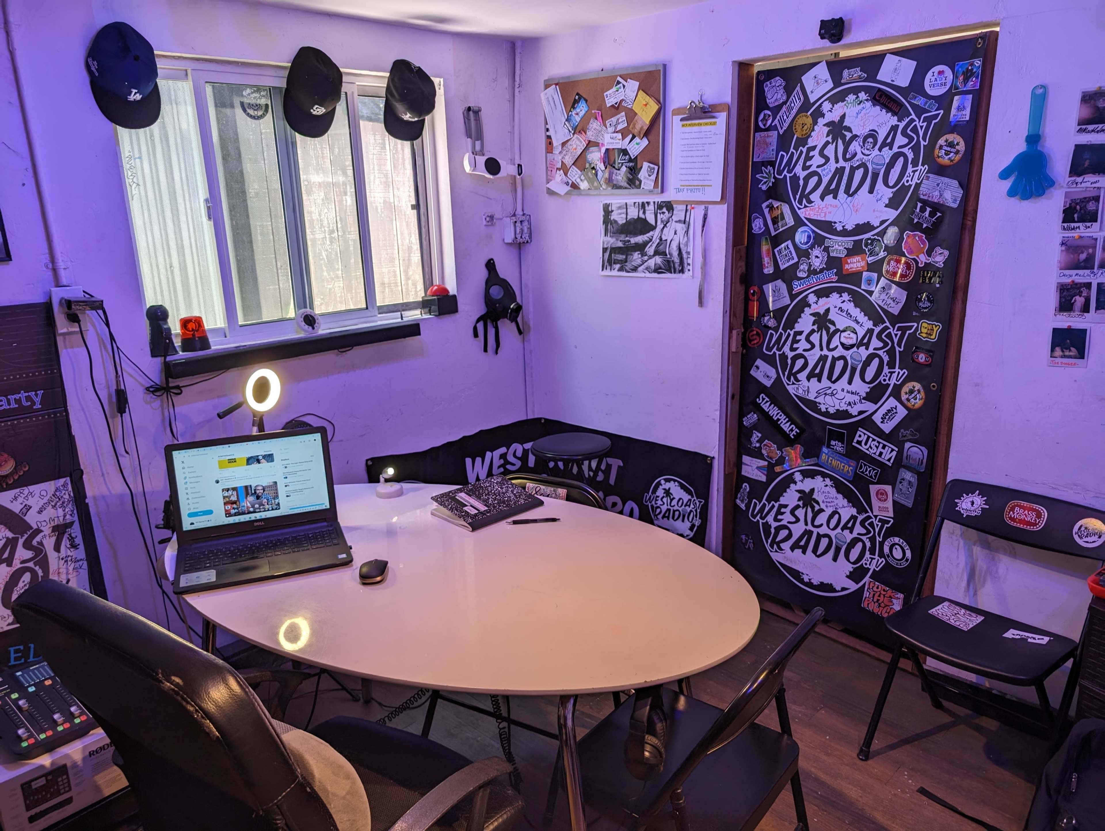 A small, decorated room with a round table, a laptop, and walls covered in various stickers and notes.