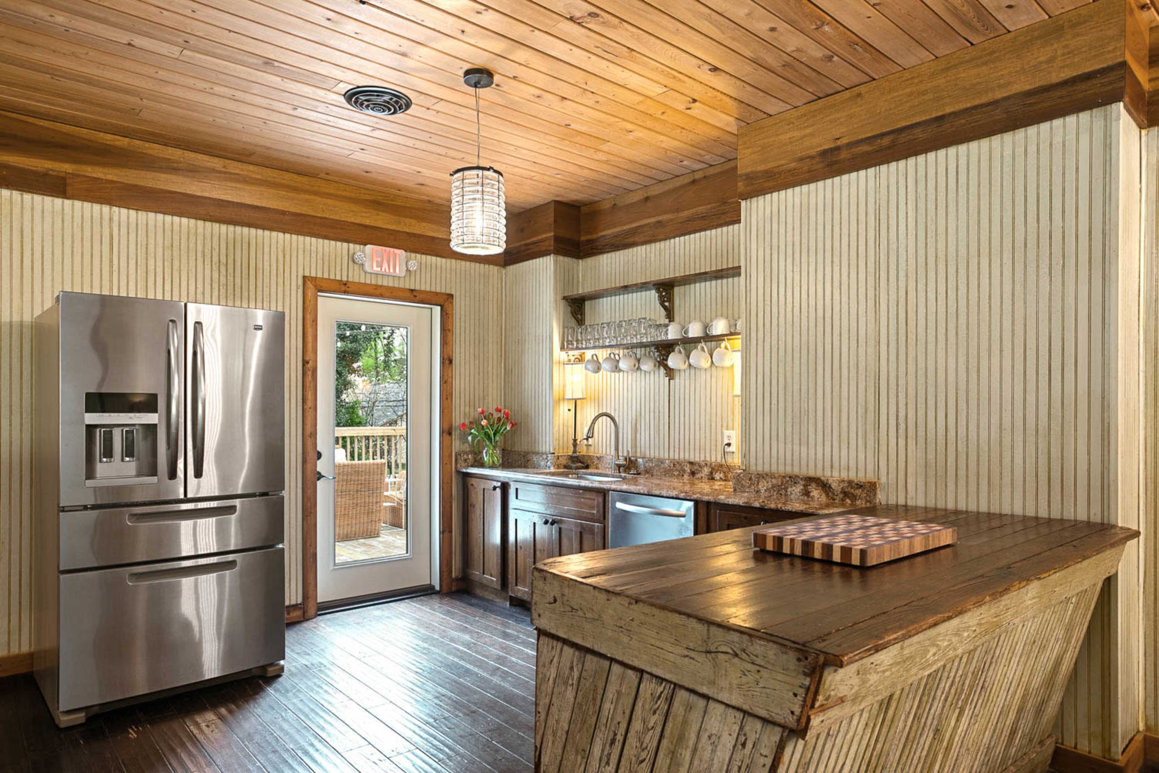 The kitchen features stainless steel appliances, wooden accents, and a bar counter with a cutting board.