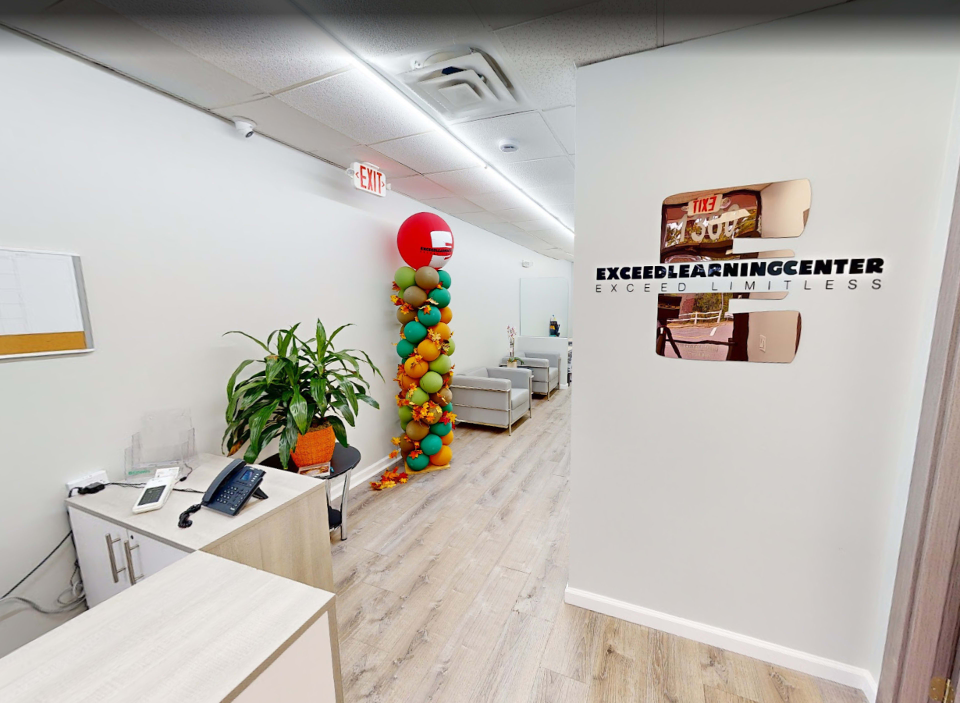 The image shows the interior of a learning center with a reception area, colorful balloon decorations, and seating arrangements along the wall.