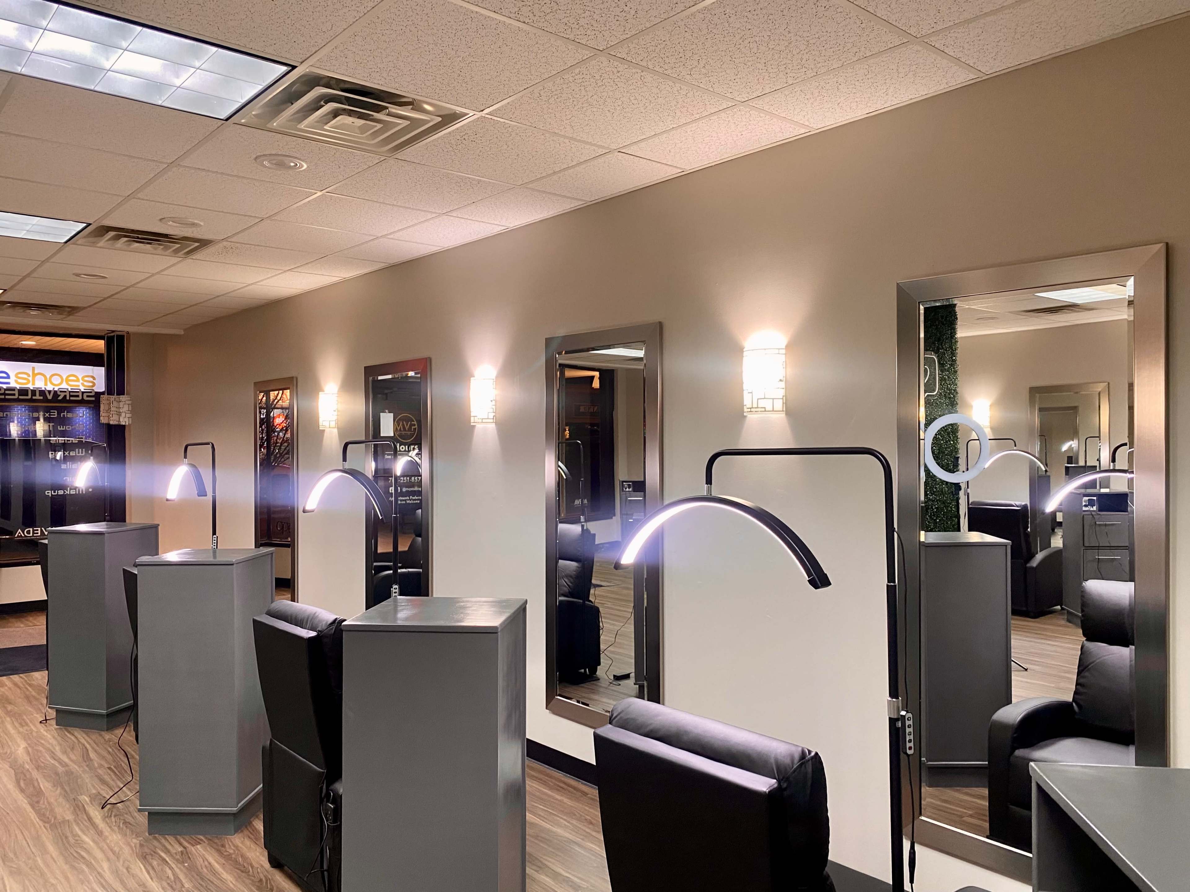 A modern salon interior with several illuminated mirrors and styling stations arranged along the walls.