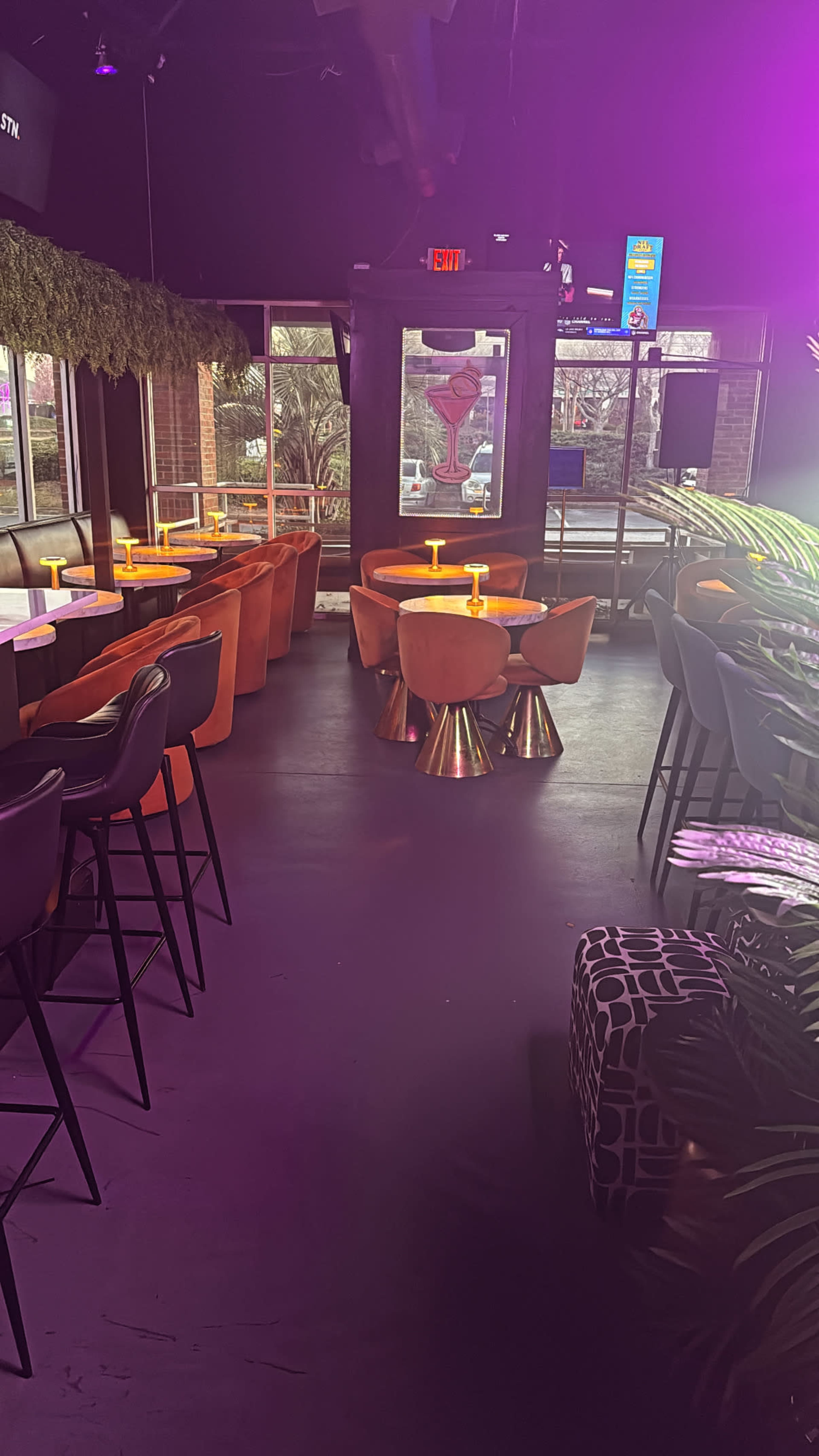 The image shows a modern lounge area with colorful seating, tables, and large windows that allow natural light to enter.