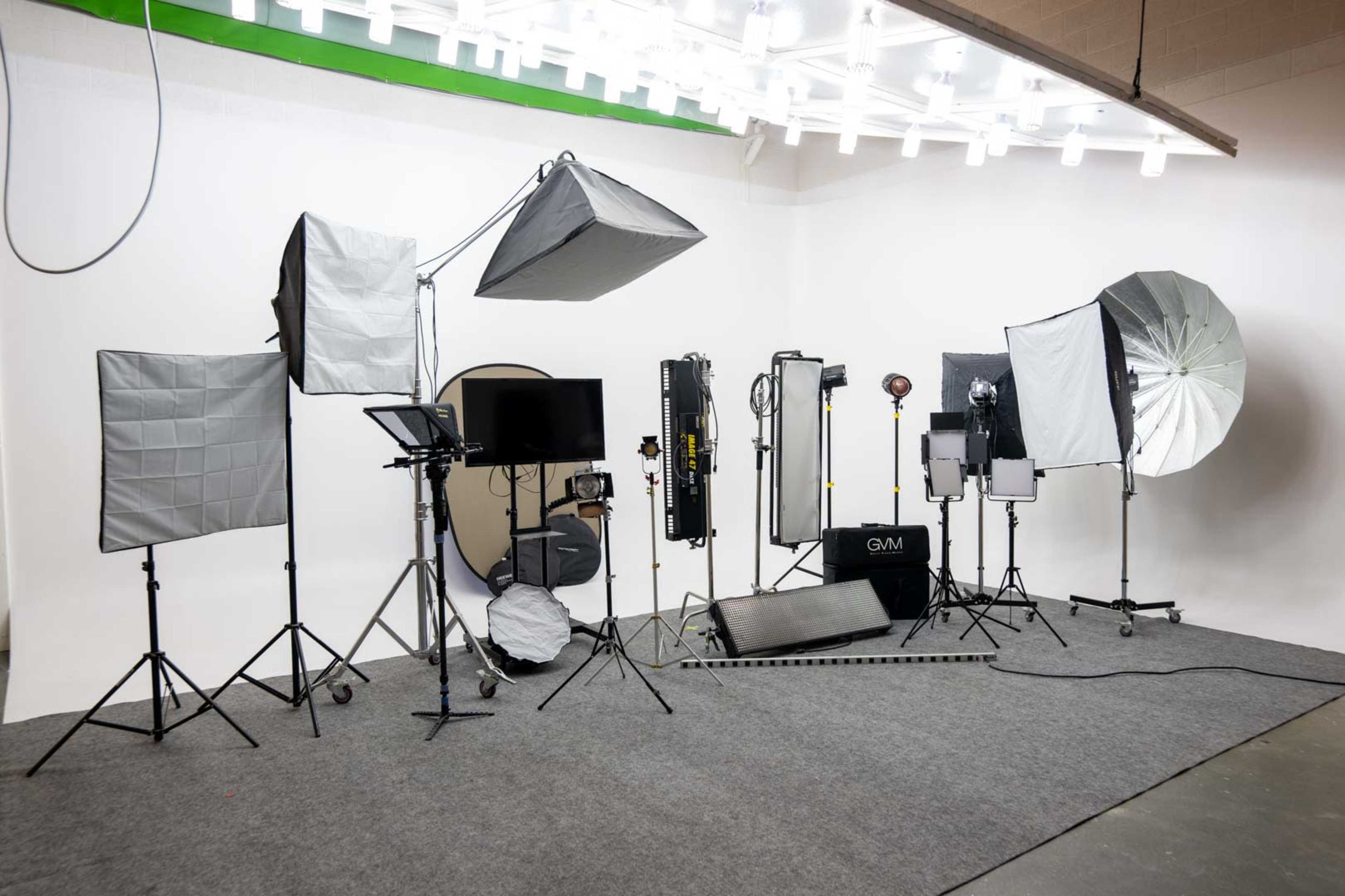 A photography studio setup featuring various lighting equipment and backdrops arranged on a gray carpeted floor.