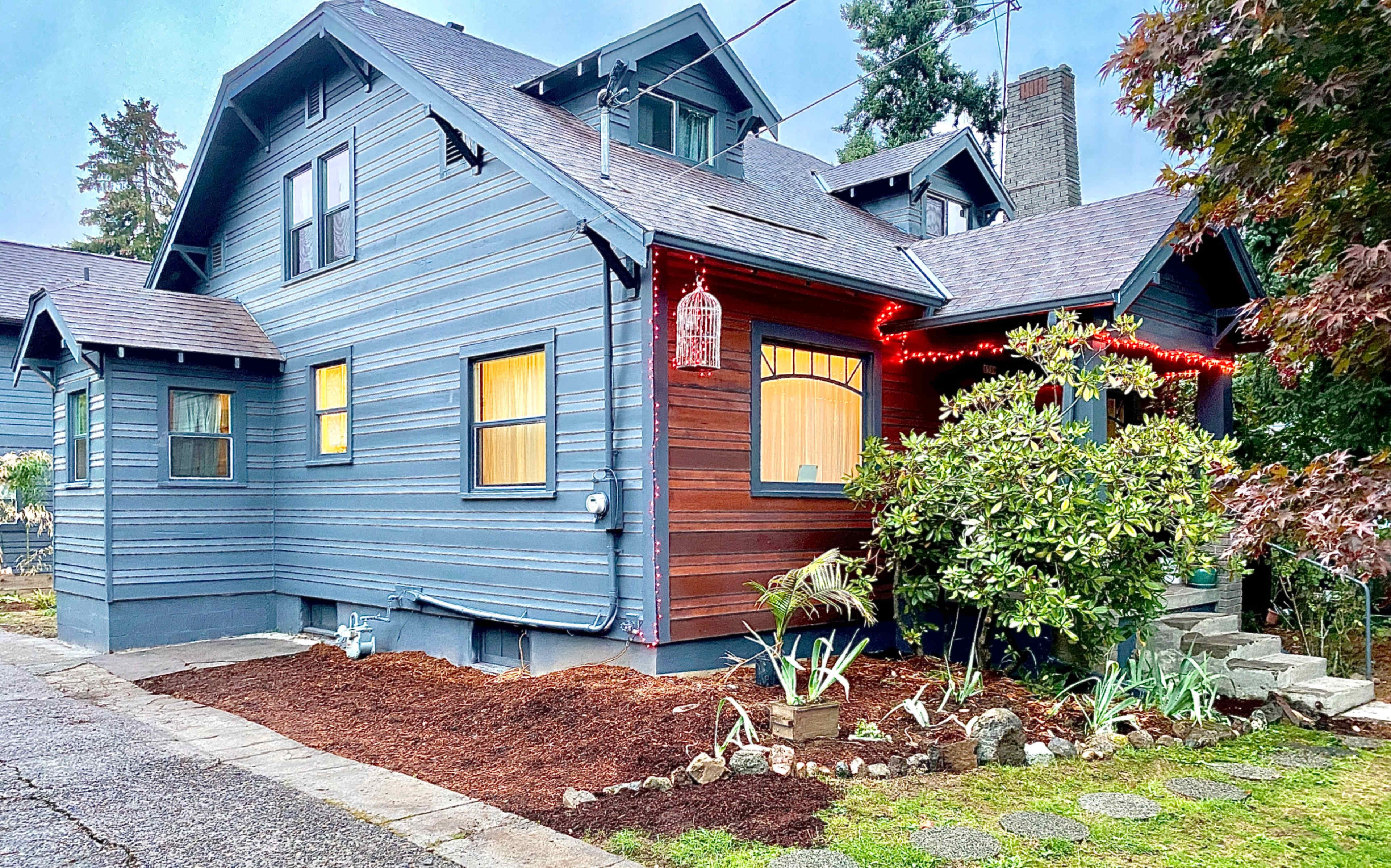 A blue and brown two-story house with decorative lights and a landscaped front yard.
