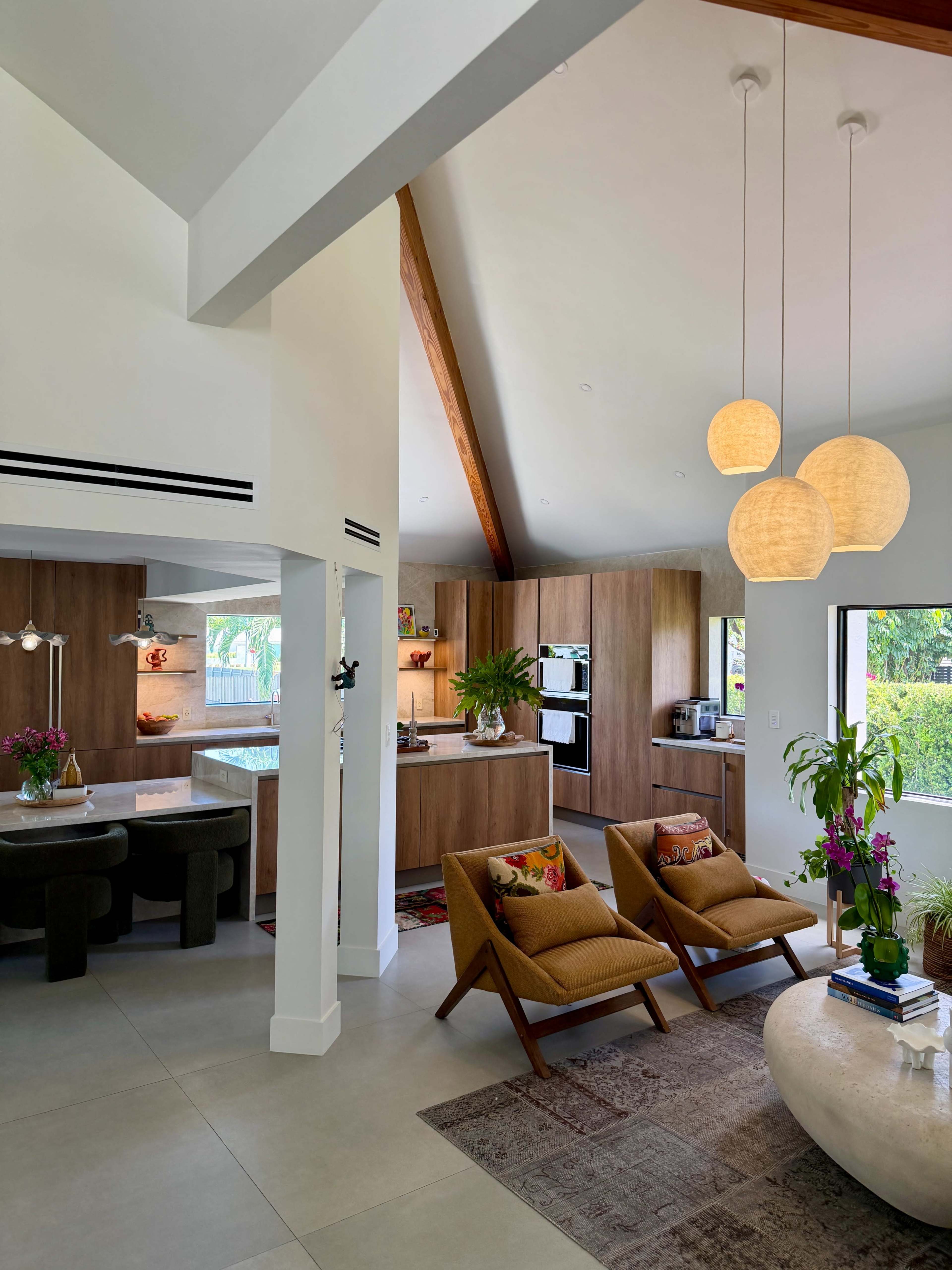 The image shows an open-concept living area with a kitchen, dining space, and two mid-century modern chairs.