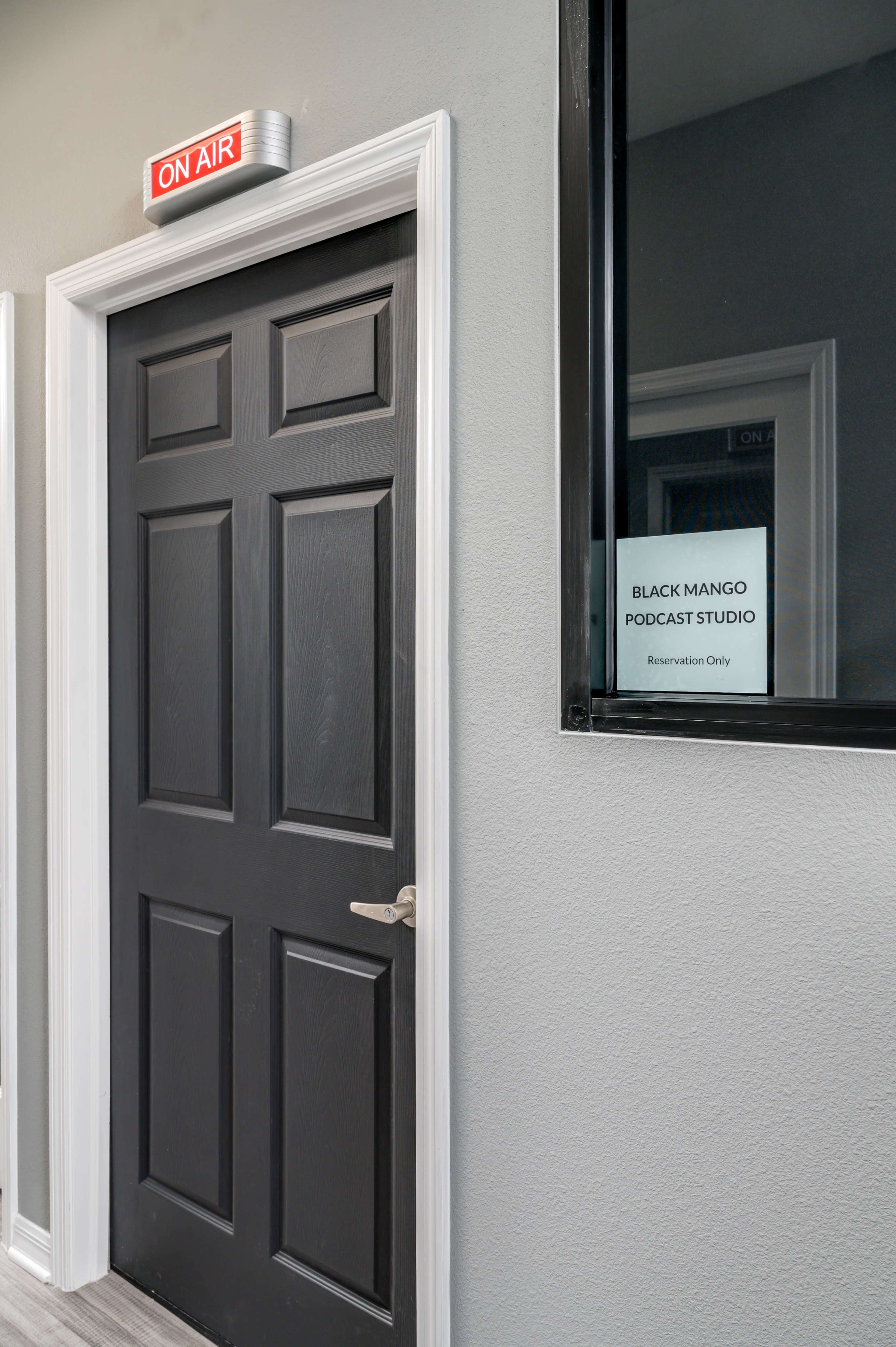 A black door labeled "ON AIR" leads to a podcast studio with a sign that reads "BLACK MANGO PODCAST STUDIO" and "Reservation Only."