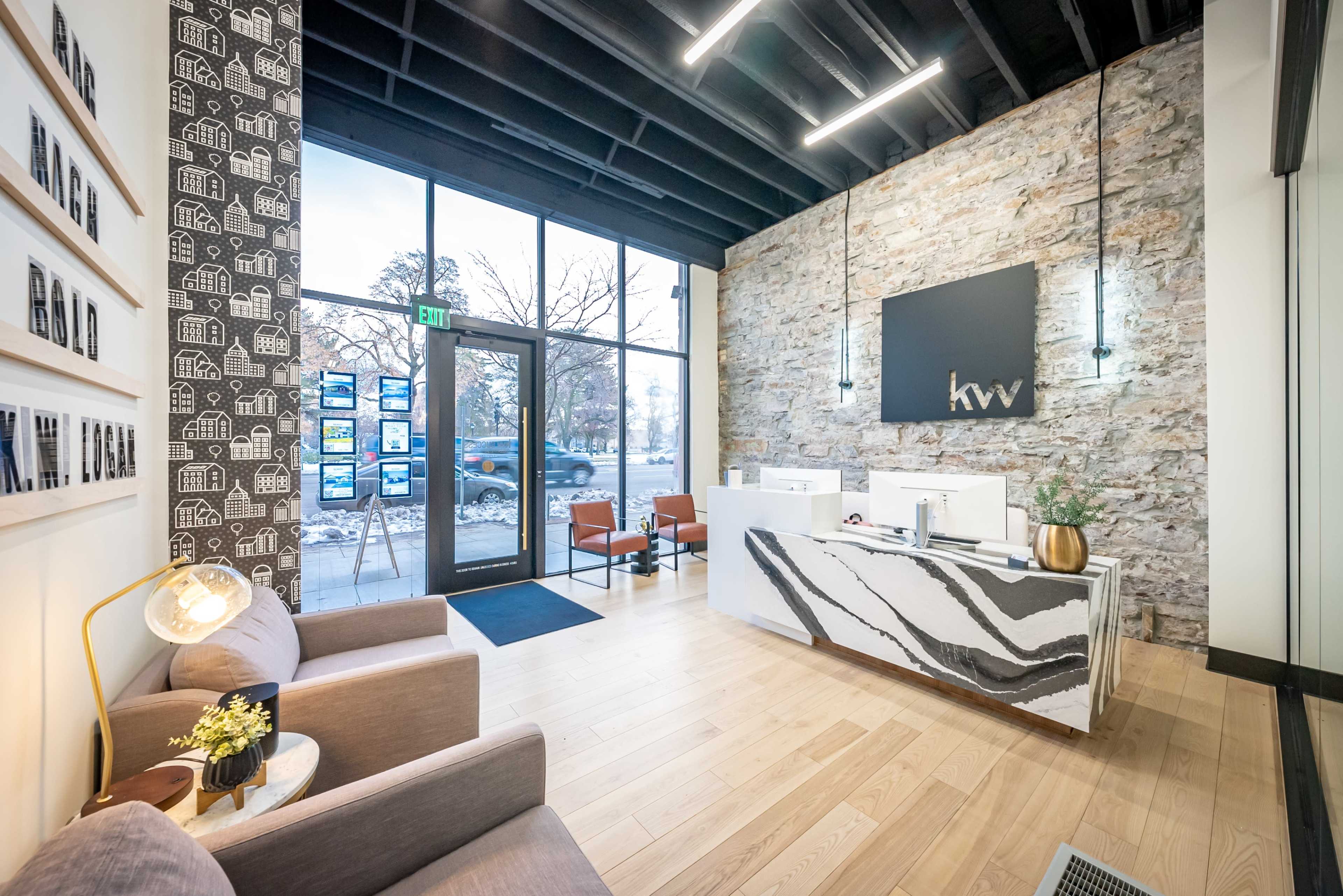 The image shows a modern reception area with a stone wall, a striped marble reception desk, and seating arrangements by large windows.