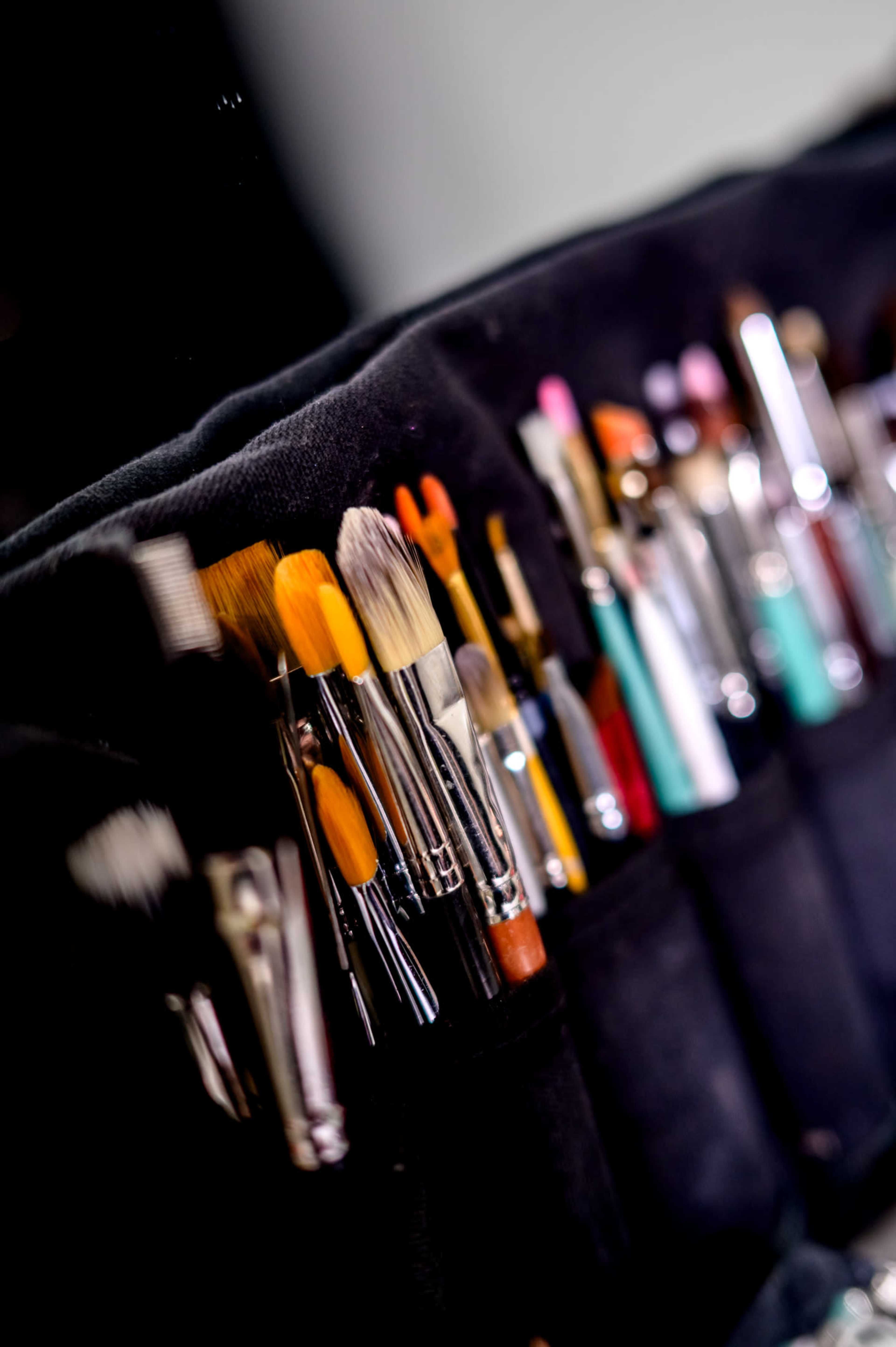 A collection of various artist brushes organized in a dark fabric holder.